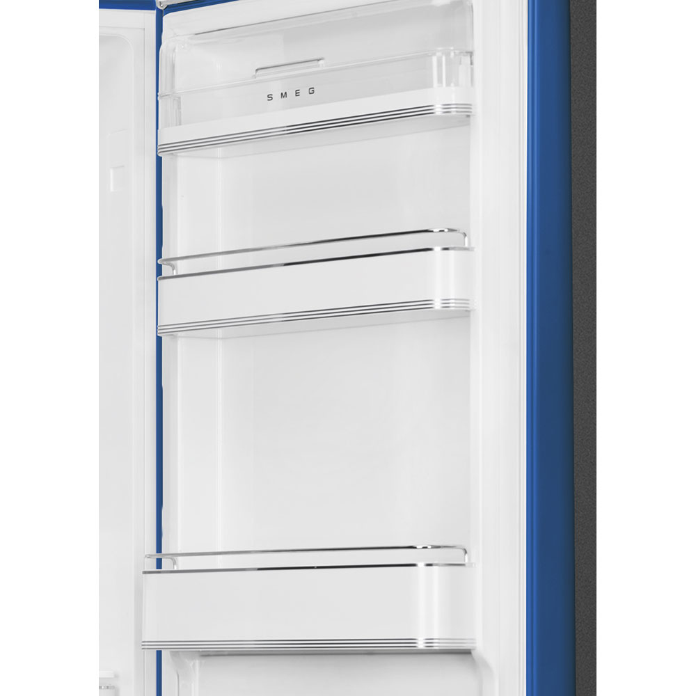 Interior de refrigerador abierto con estantes blancos y ribete azul. La marca 'SMEG' es visible. El marco de la puerta es azul.