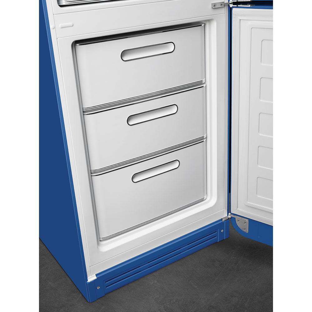 Refrigerador azul abierto con tres cajones blancos. La puerta está abierta revelando el interior. Piso oscuro y alrededores blancos.