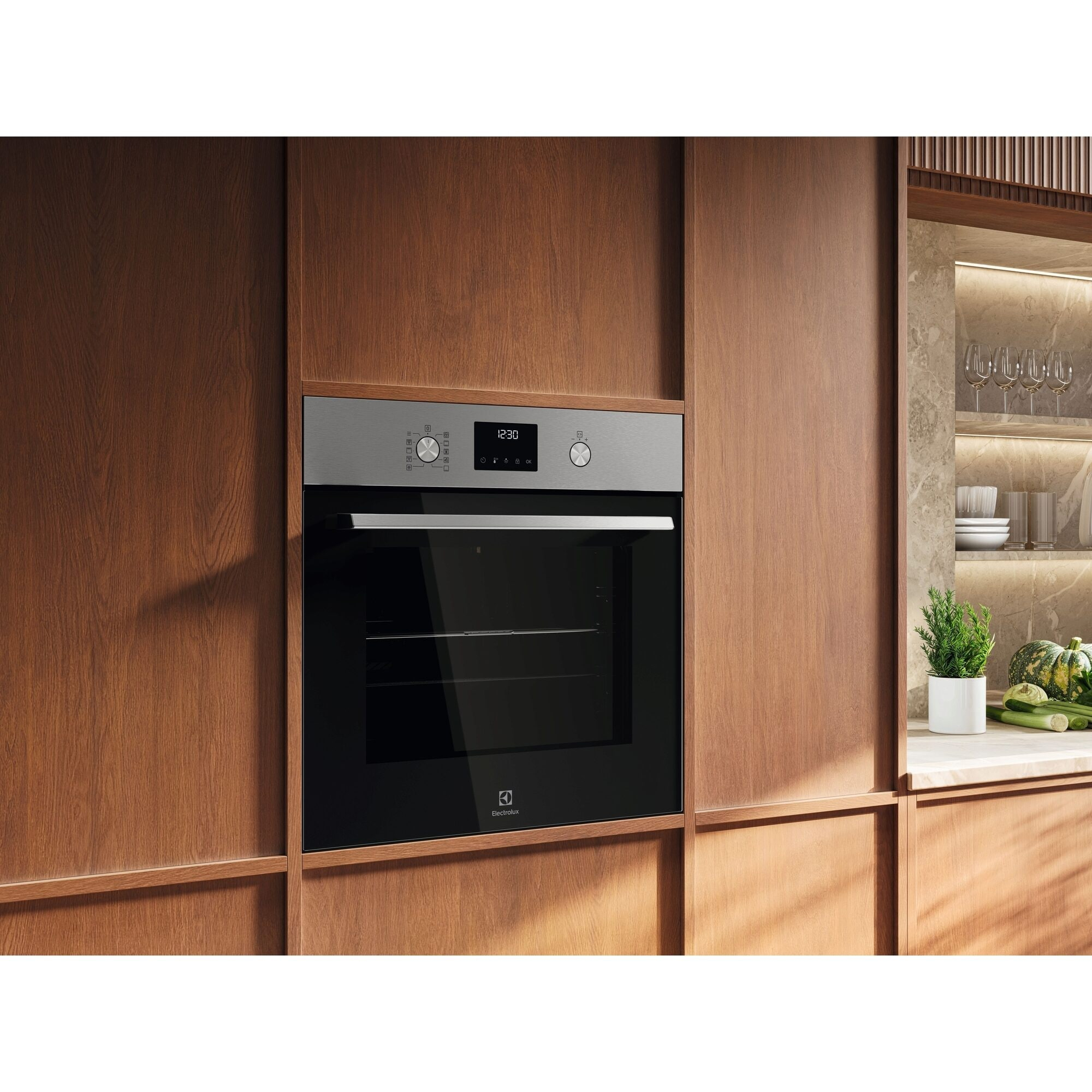 Piekarnik do zabudowy z czarnymi szklanymi drzwiami, w drewnianej szafce. Na wyświetlaczu piekarnika 12:30. Po prawej półka ze szklankami.