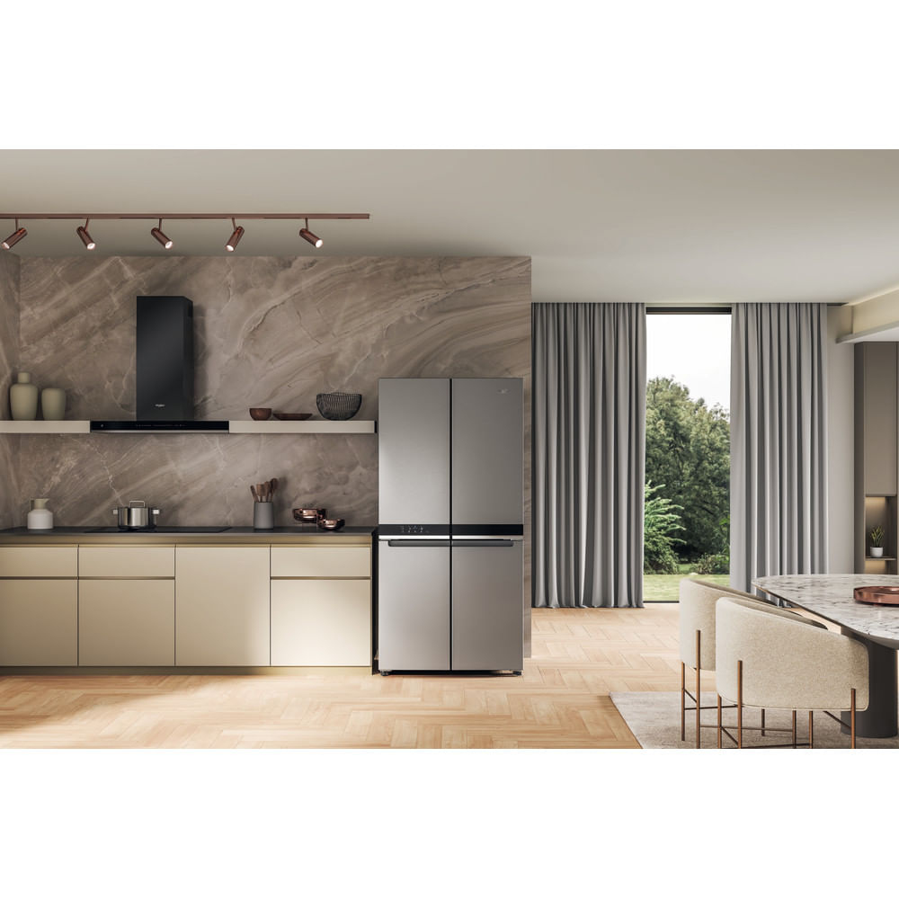 Moderne Küche mit großem Kühlschrank aus Edelstahl. Beige Schränke und eine marmorartige Wand sind sichtbar.
