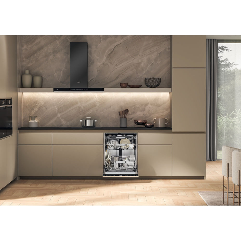 Interno cucina con lavastoviglie aperta, armadi e cappa nera. Piatti all'interno della lavastoviglie. Pavimento in legno.