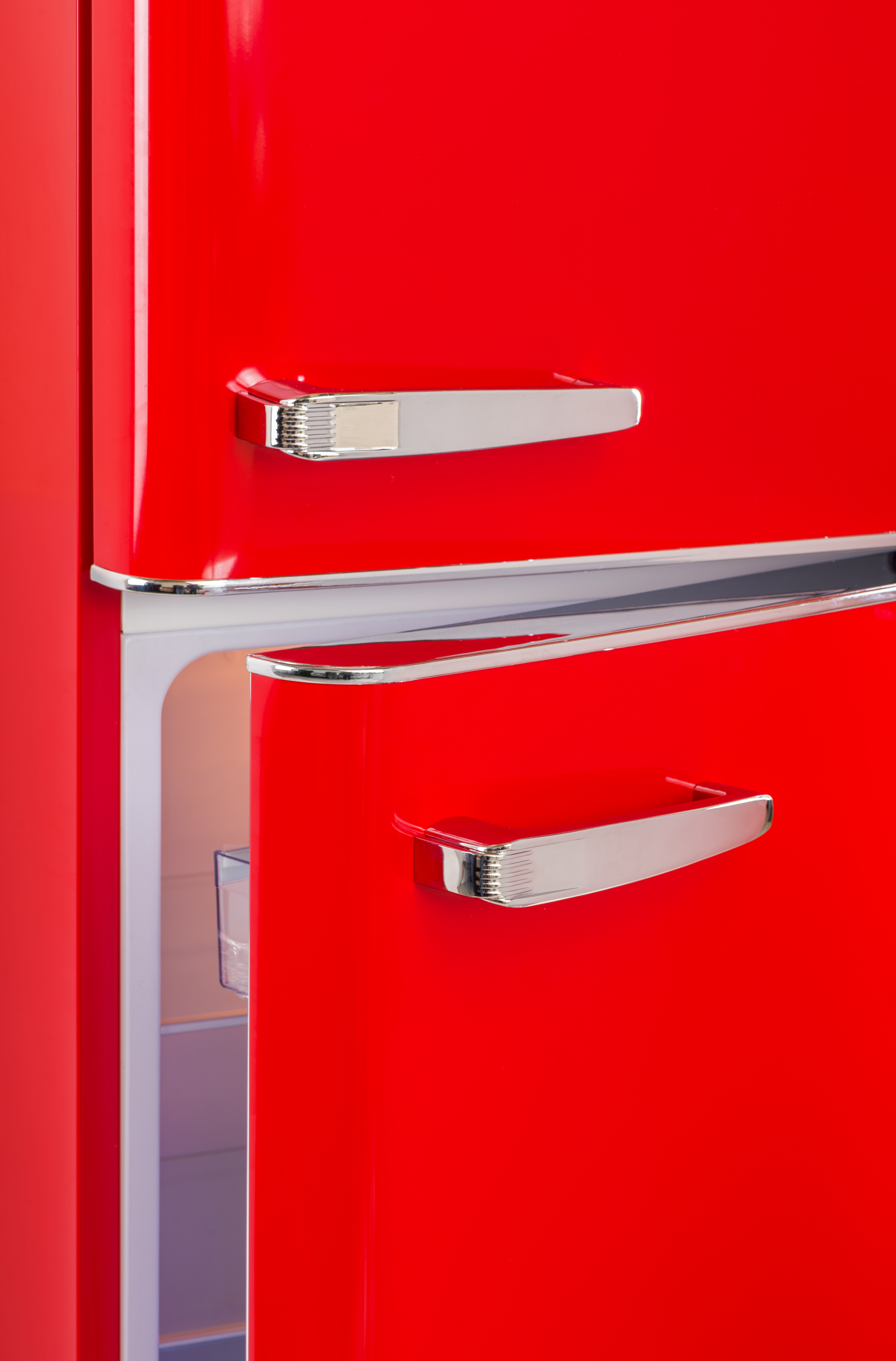 Ein roter Kühlschrank mit offener Tür. Es hat einen Chromgriff und einen weißen Innenraum.