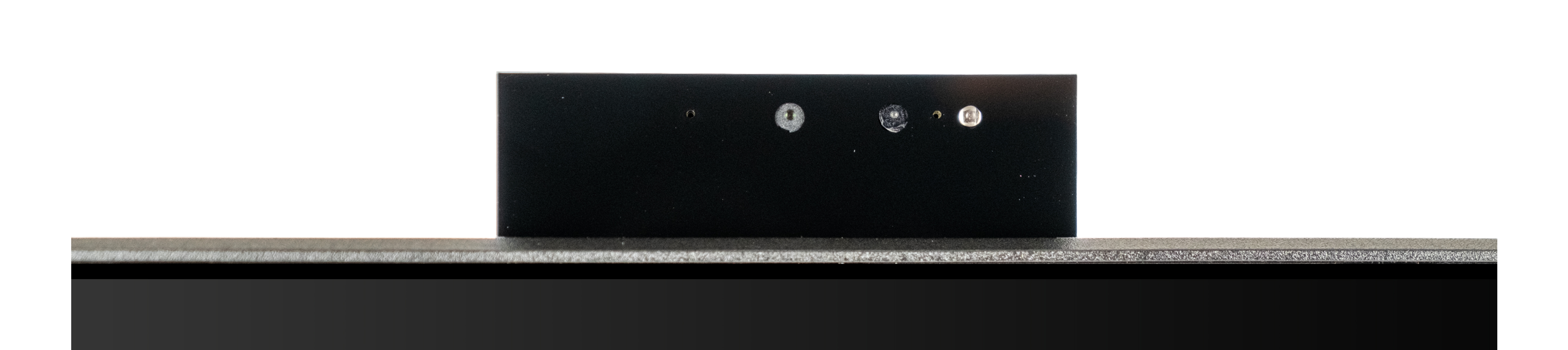 Zbliżenie czarnego urządzenia z trzema małymi otworami i srebrną podstawą na białym tle.