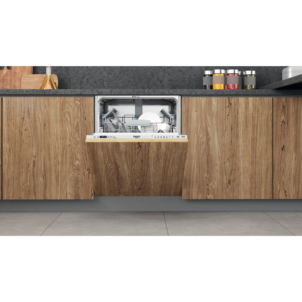 Una lavastoviglie con la porta aperta. È integrata in un mobile di legno con piano di lavoro grigio. All'interno sono visibili piatti.
