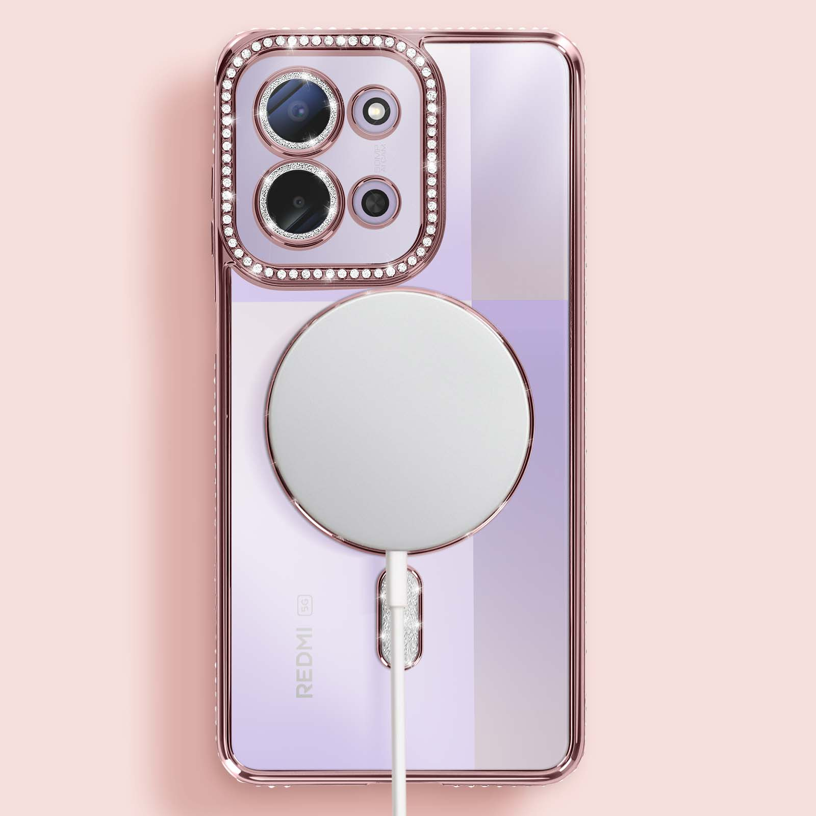 Een telefoonhoesje met uitsparingen voor de camera en een oplader. De hoes is roségoudkleurig met strass. De telefoon heeft een witte oplaadschijf.