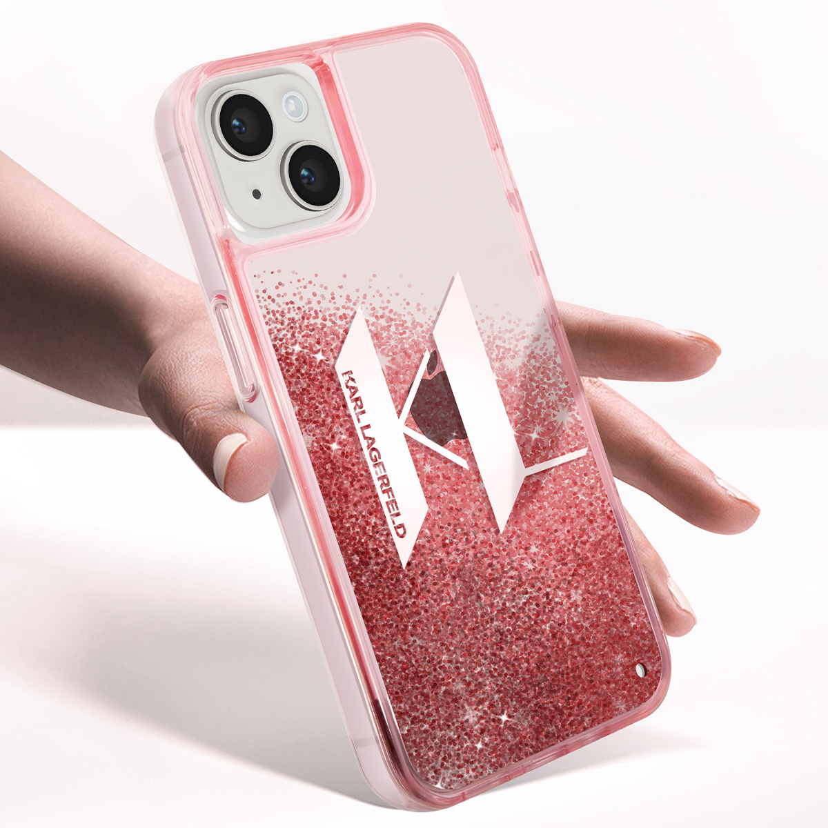 Una mano tiene una custodia rosa per iPhone con glitter e logo Karl Lagerfeld.