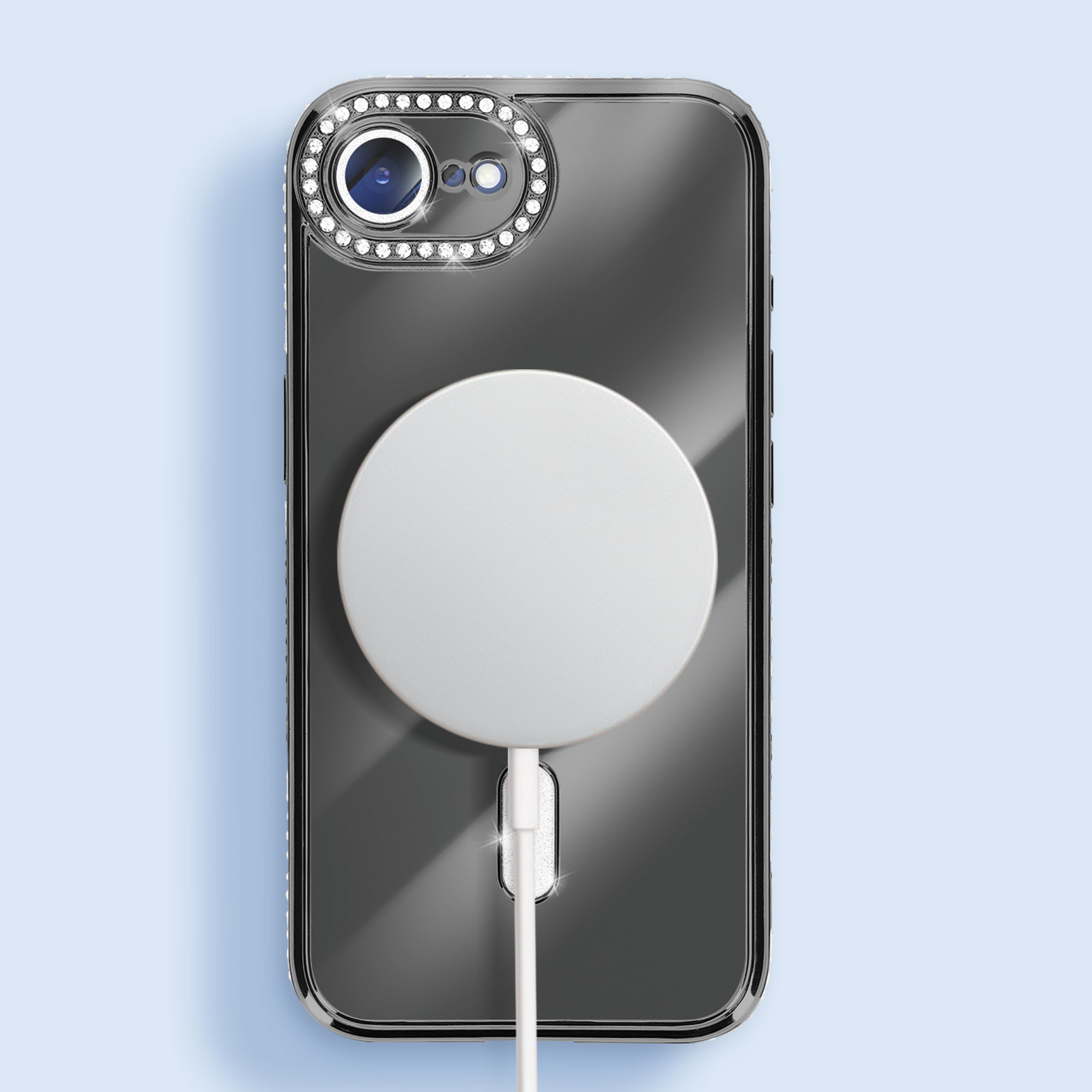 Een telefoon in een hoesje met een magnetische oplader. De hoes heeft een cameraring met strass en een wit oplaadpad.