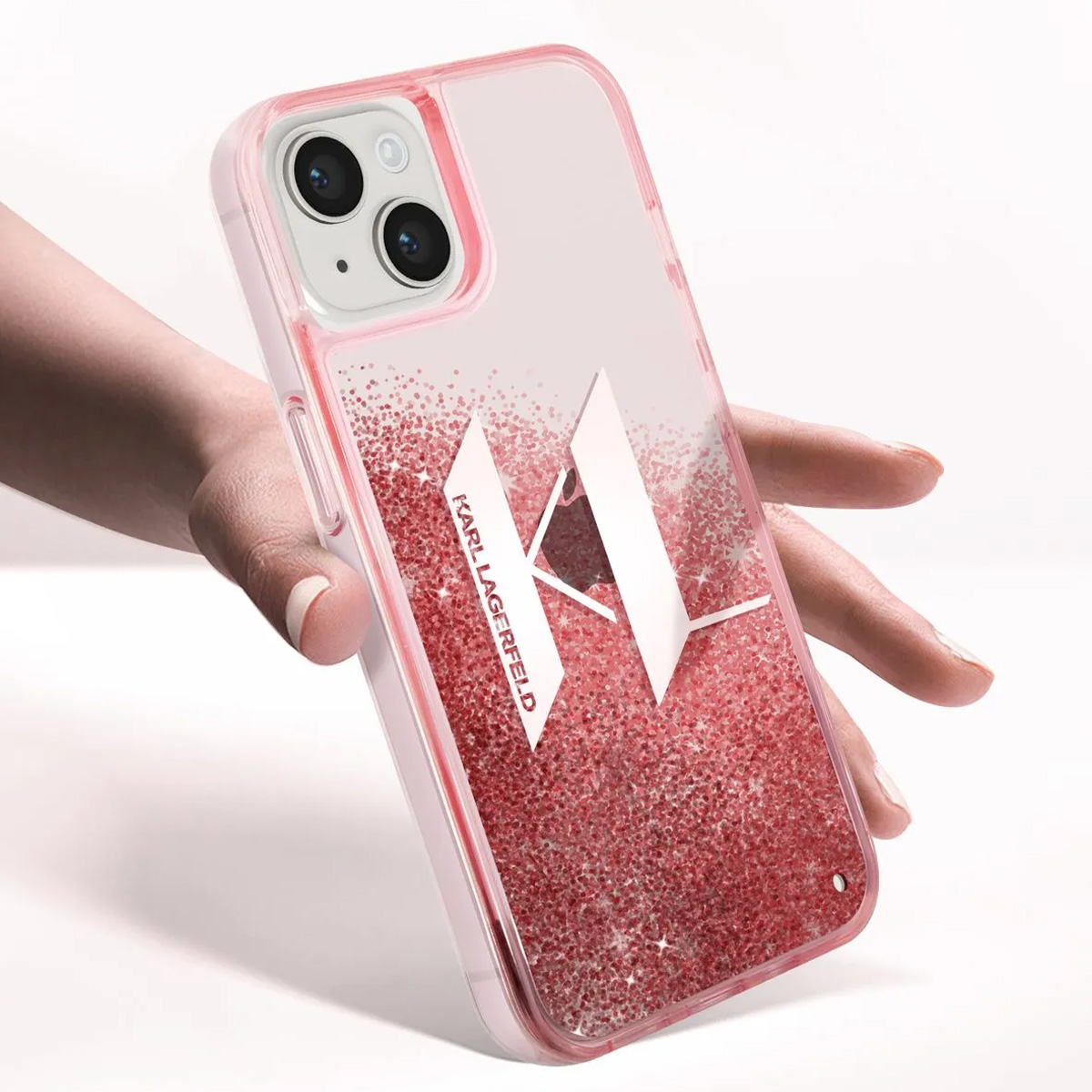 Una mano tiene una custodia rosa per telefono con glitter e il logo bianco Karl Lagerfeld. Il telefono ha due fotocamere.
