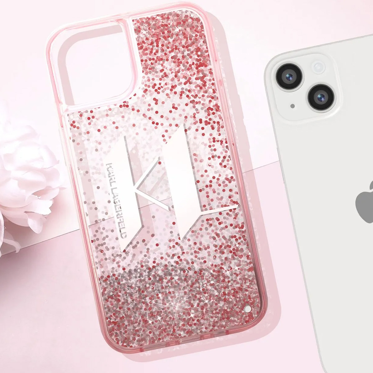 Una custodia per telefono con glitter e logo 'K' accanto a un iPhone bianco. Sfondo rosa e un fiore a sinistra.