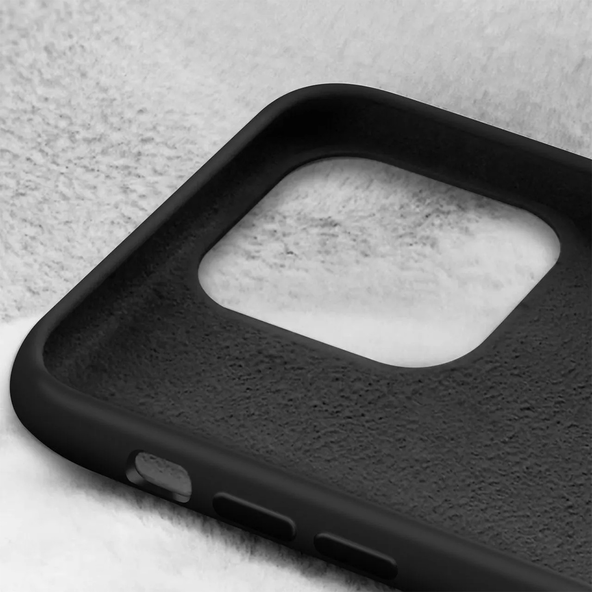 Primo piano di una custodia per telefono nera con superficie strutturata, su sfondo grigio chiaro sfocato.