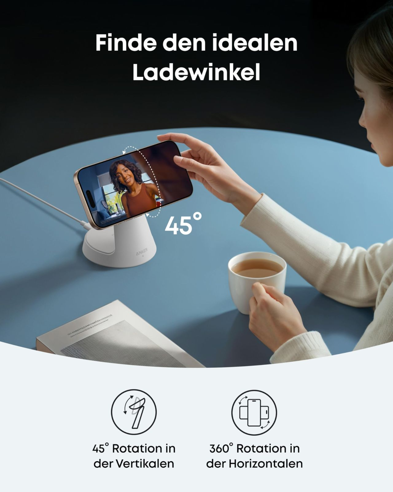 Eine Frau hält ein Telefon an einem Ladegerät. Das Telefon zeigt ein Video. Auf dem Tisch steht eine Tasse Tee.