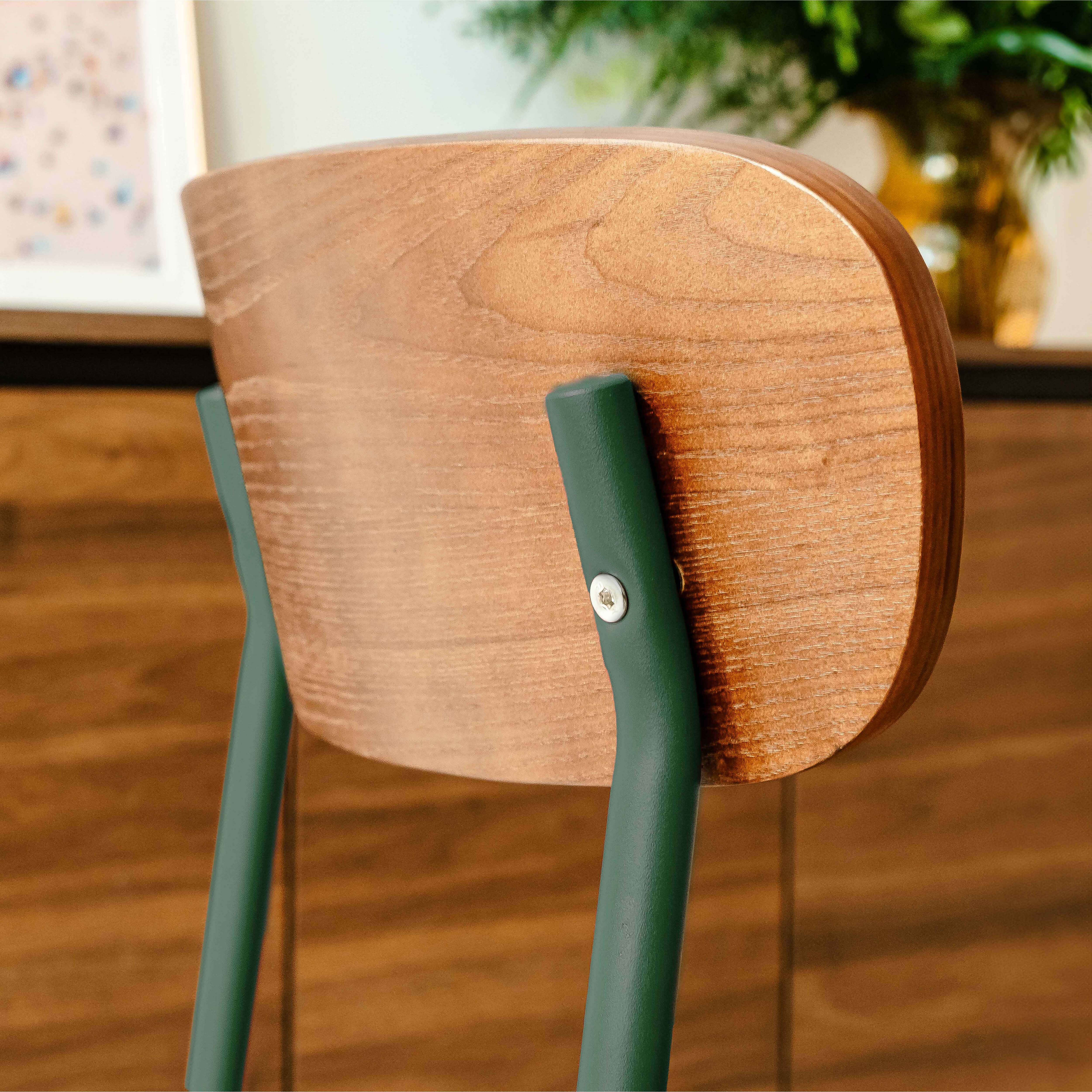 Nahaufnahme der Rückseite eines Holzstuhls mit dunkelgrünen Beinen. Das Holz hat eine natürliche Maserung.