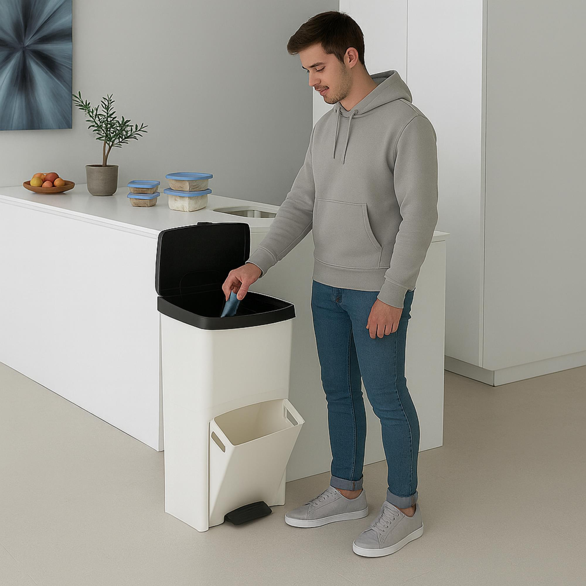 Hombre con sudadera gris y jeans metiendo objeto en un basurero blanco y negro en una cocina.