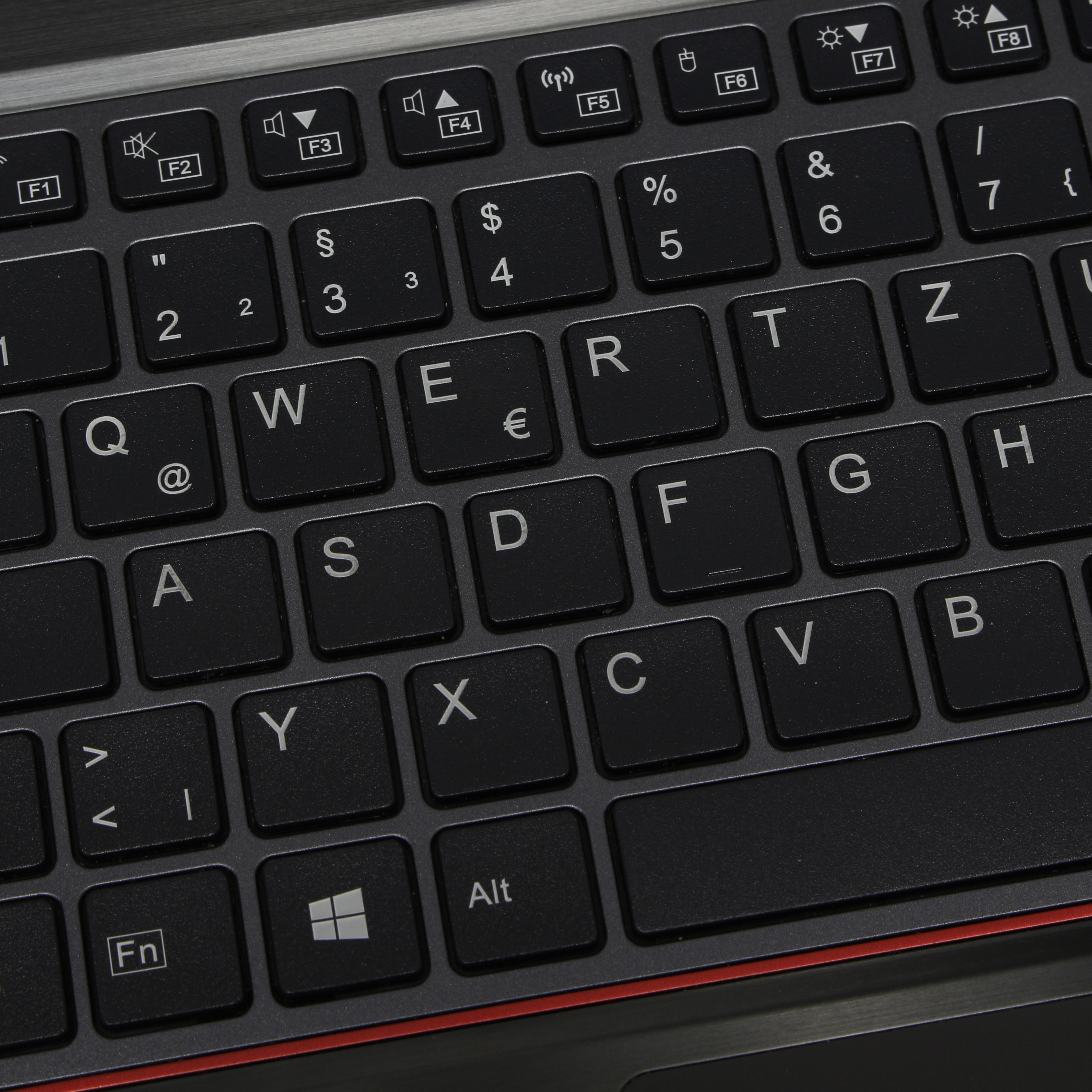 Gros plan sur un clavier d'ordinateur portable noir, avec des lettres et des symboles blancs. Ligne rouge visible.