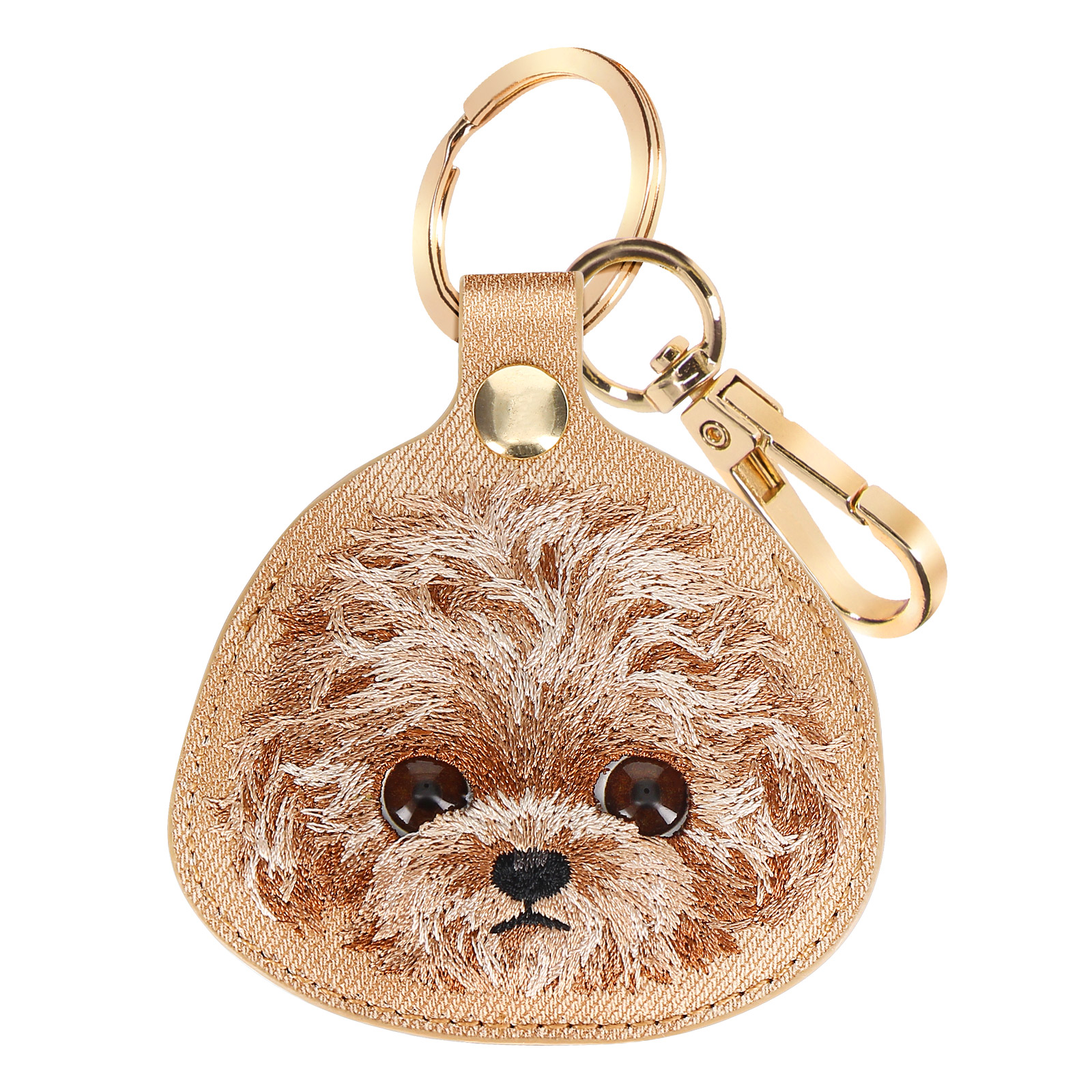 Un portachiavi color oro con una faccia di cane ricamata. Ha un anello e un fermaglio dorati. Lo sfondo è bianco.