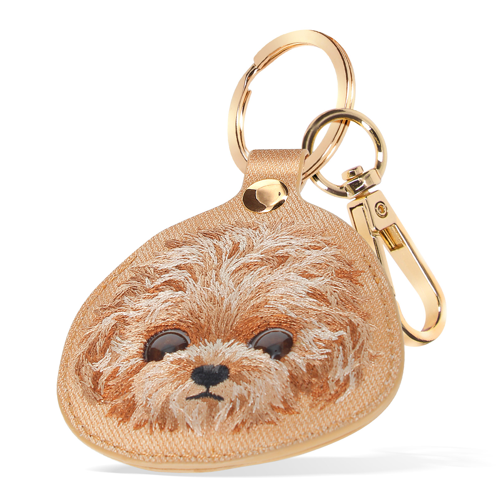 Un portachiavi a forma di cane. Ha ricami marroni, finiture dorate e un passante in pelle.