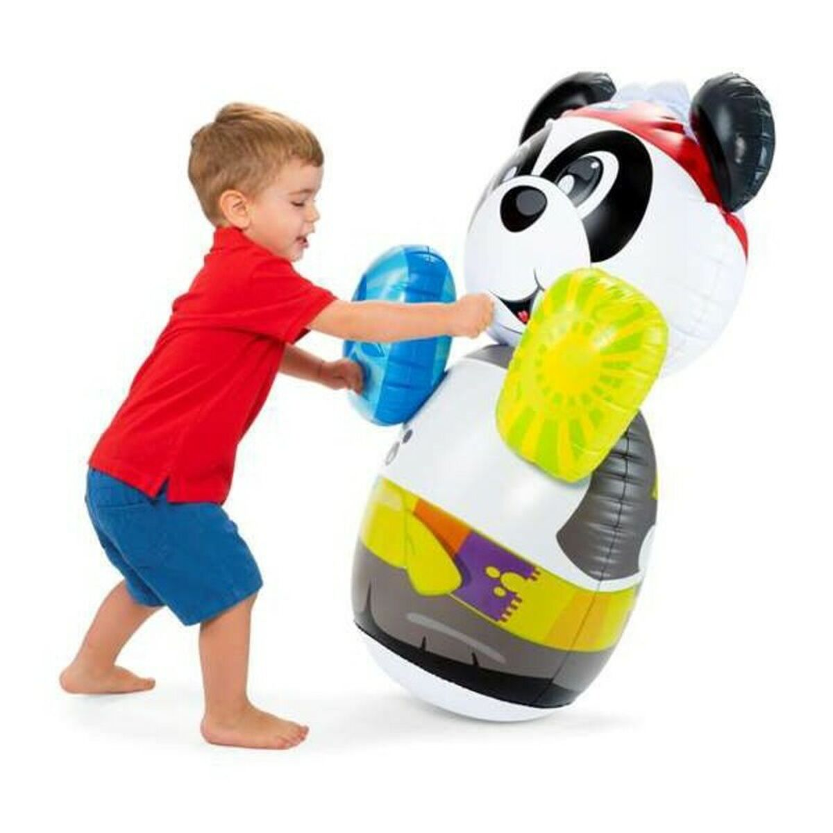 Un niño pequeño con camisa roja y pantalones cortos azules jugando con un juguete inflable de panda. El niño está empujando el juguete.