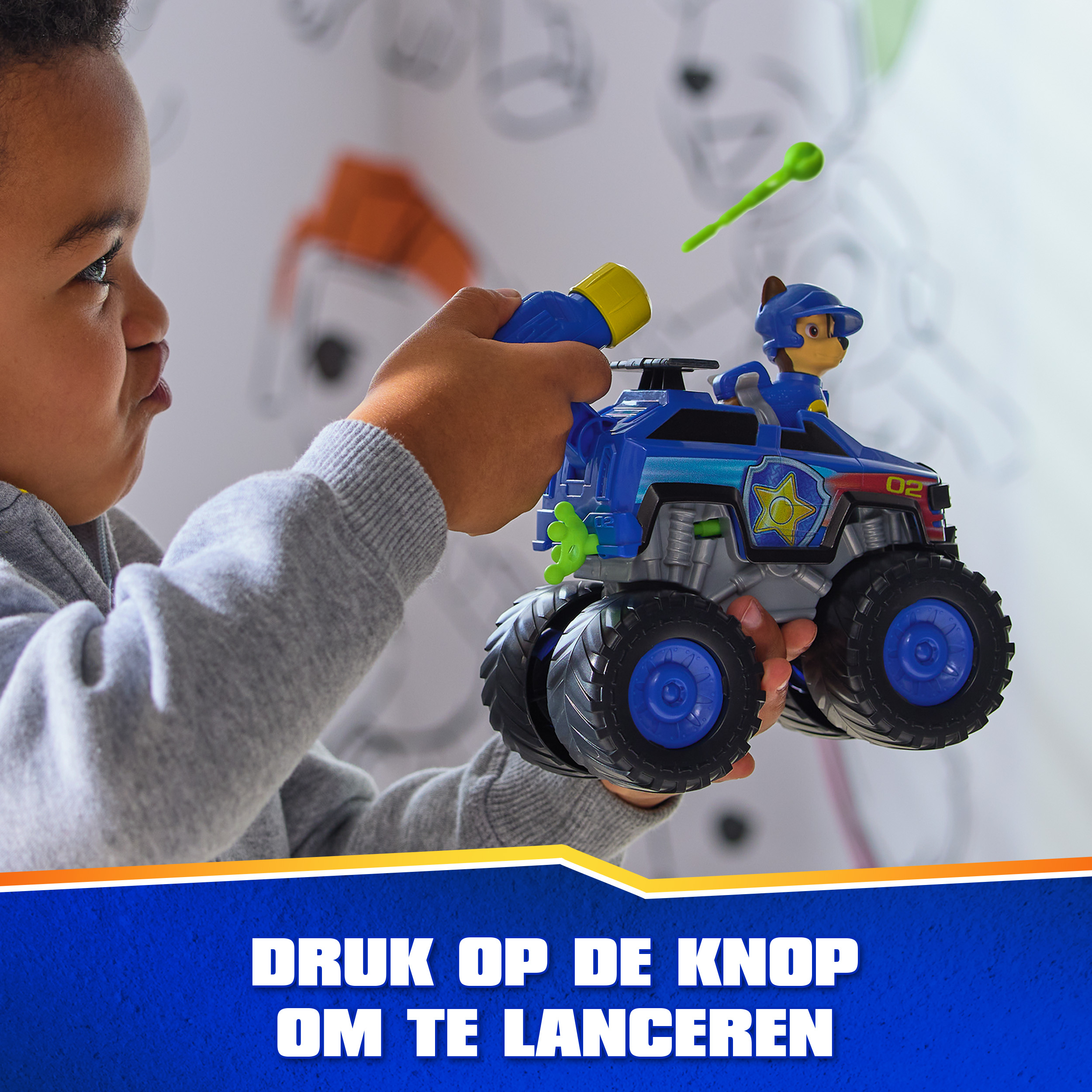 Dziecko trzyma niebieski samochodzik z figurką. Zielony pocisk w powietrzu. Tekst na dole.