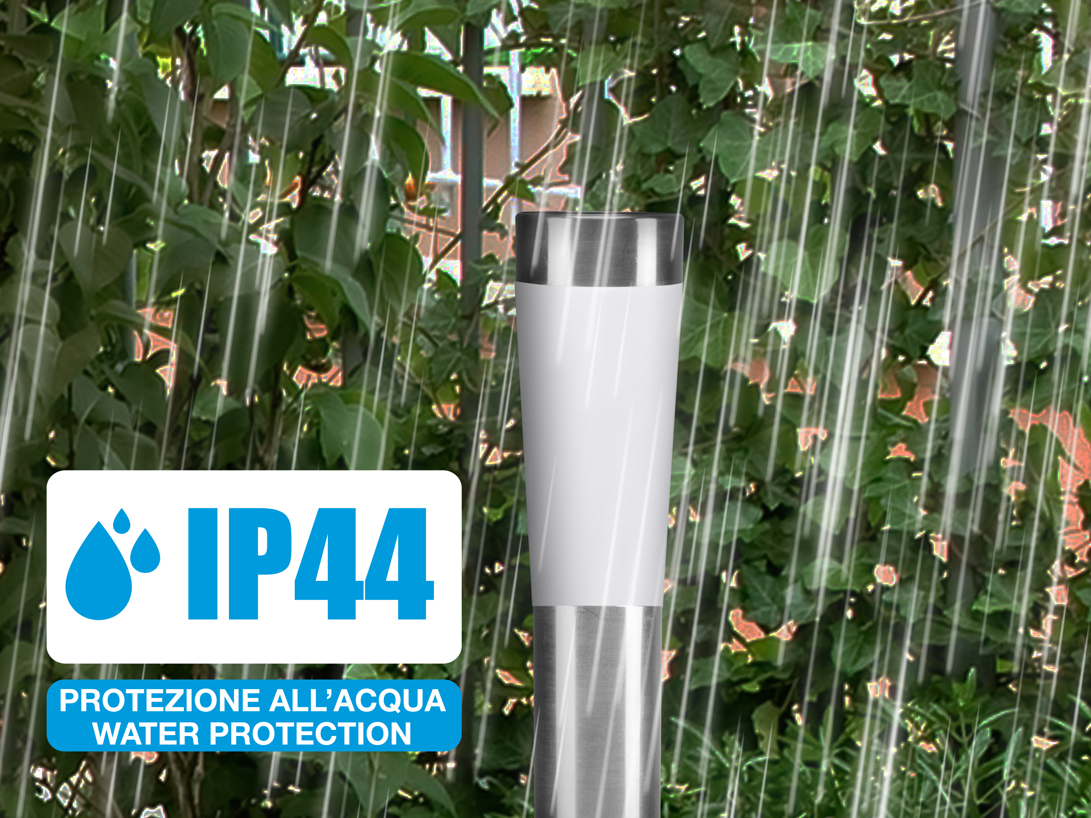 Una lampada bianca e argento sotto la pioggia. Visibile un cartello di protezione dall'acqua IP44, con fogliame verde.
