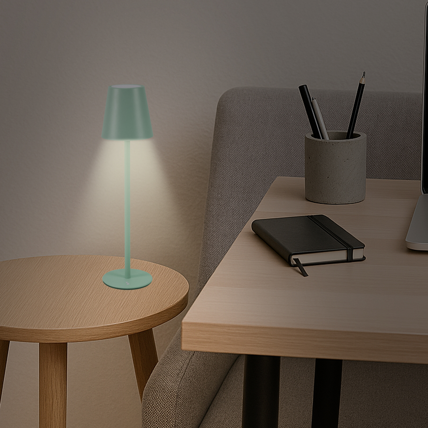 Una lampada verde menta su un tavolo di legno illumina la scena. Un taccuino, penne e un laptop sono su una scrivania accanto a una sedia grigia.