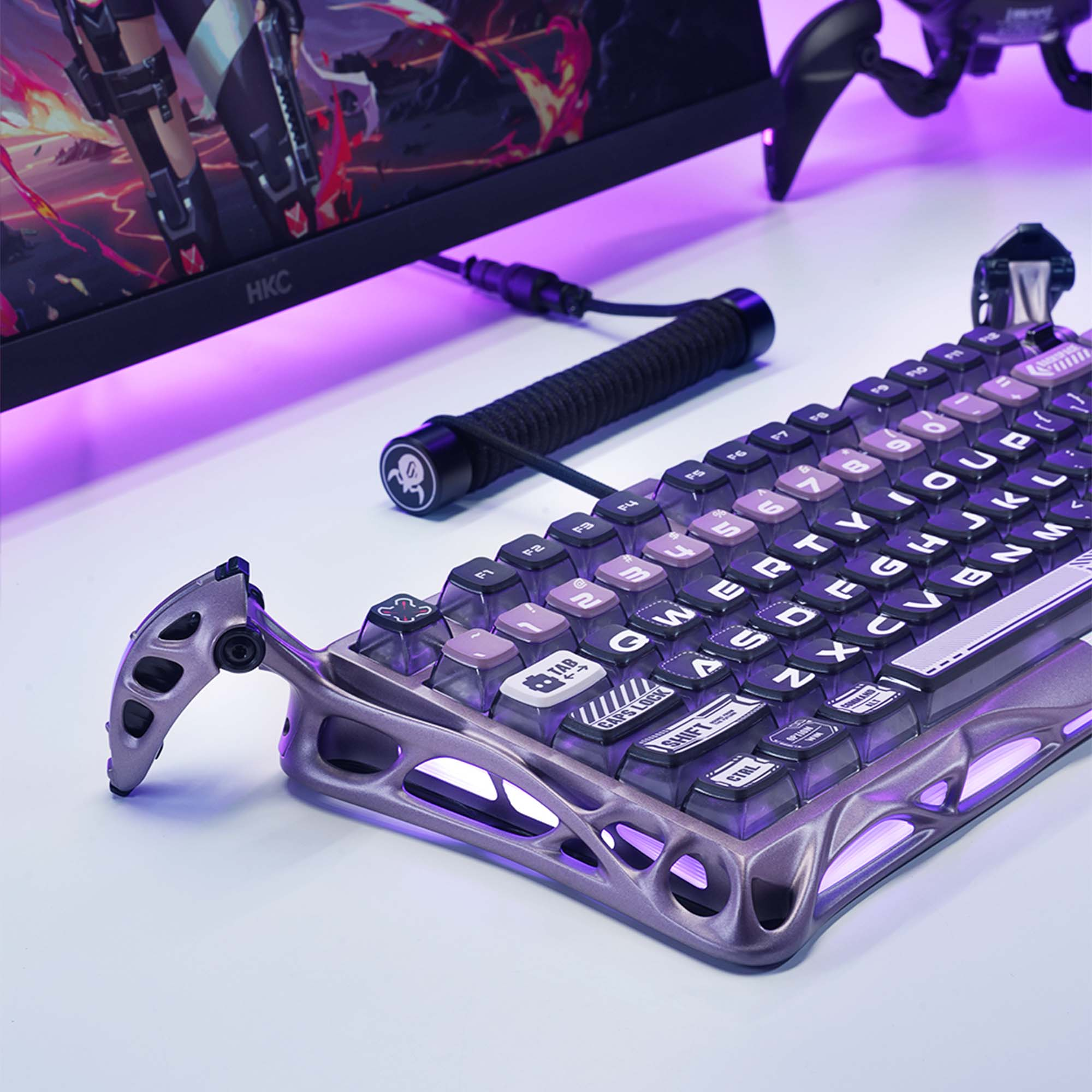 Klawiatura dla graczy z fioletowymi akcentami, klawiszami i oświetleniem. Z tyłu monitor z grafiką z gry.