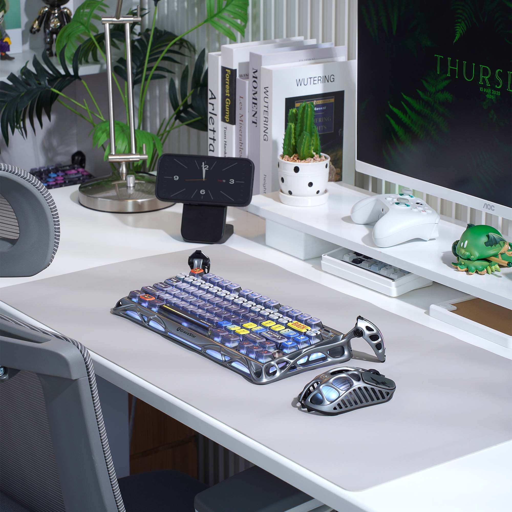 Konfiguracja biurka z klawiaturą, myszą, monitorem, książkami, zegarem, roślinami i kontrolerem.