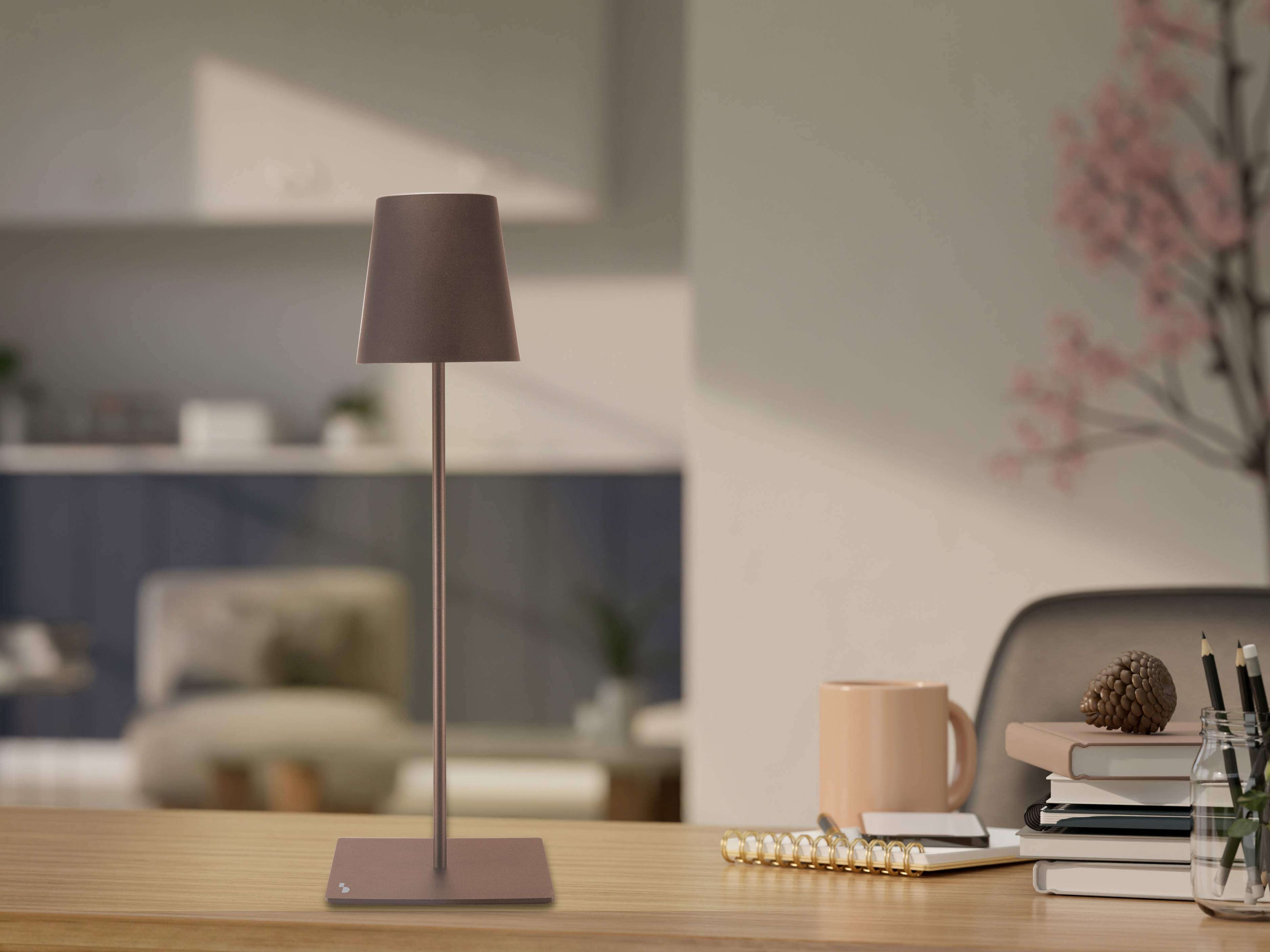 Una lampada da scrivania, libri, una tazza e matite sono su una scrivania di legno. Uno sfondo sfocato mostra una stanza.