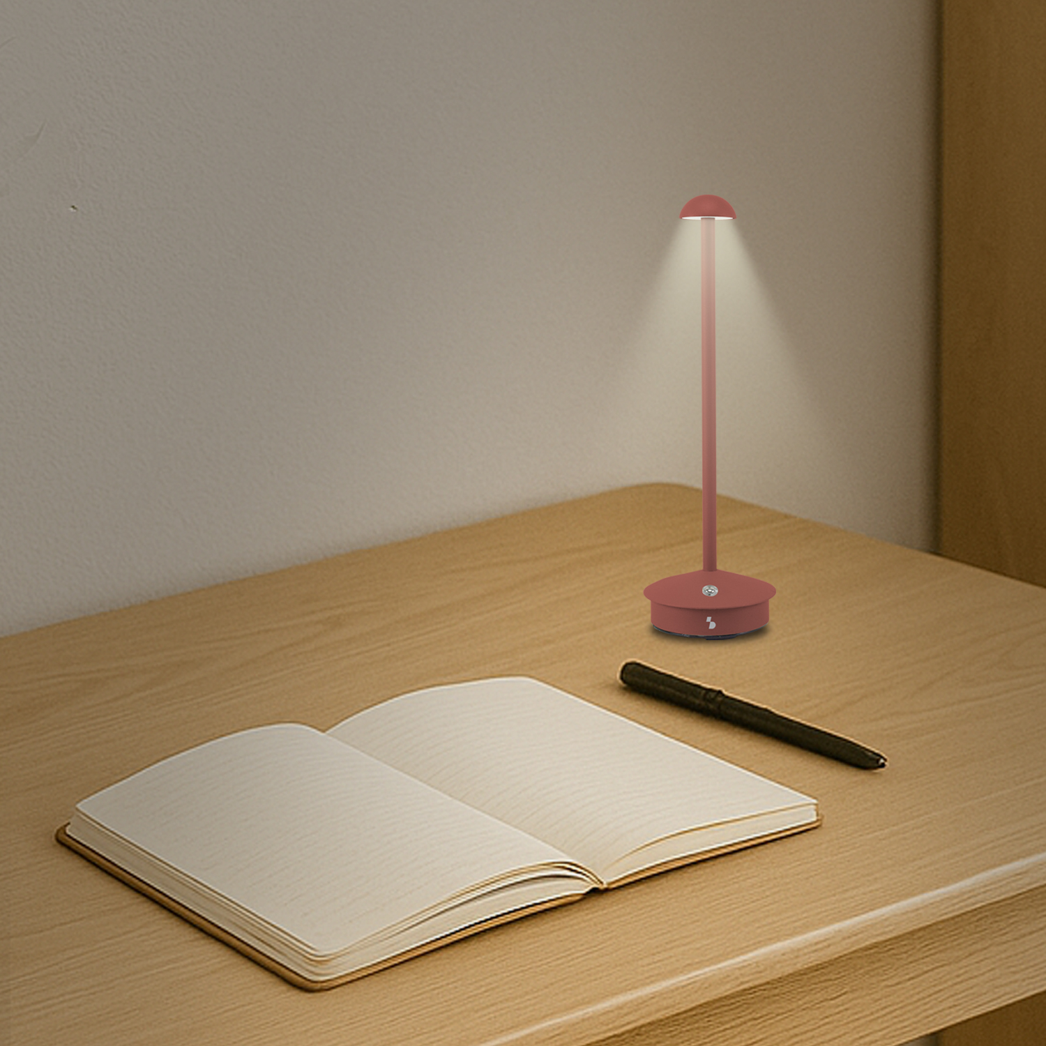 Una scrivania con un taccuino, una penna e una lampada. La lampada è accesa, che illumina la scrivania. Il taccuino è aperto.