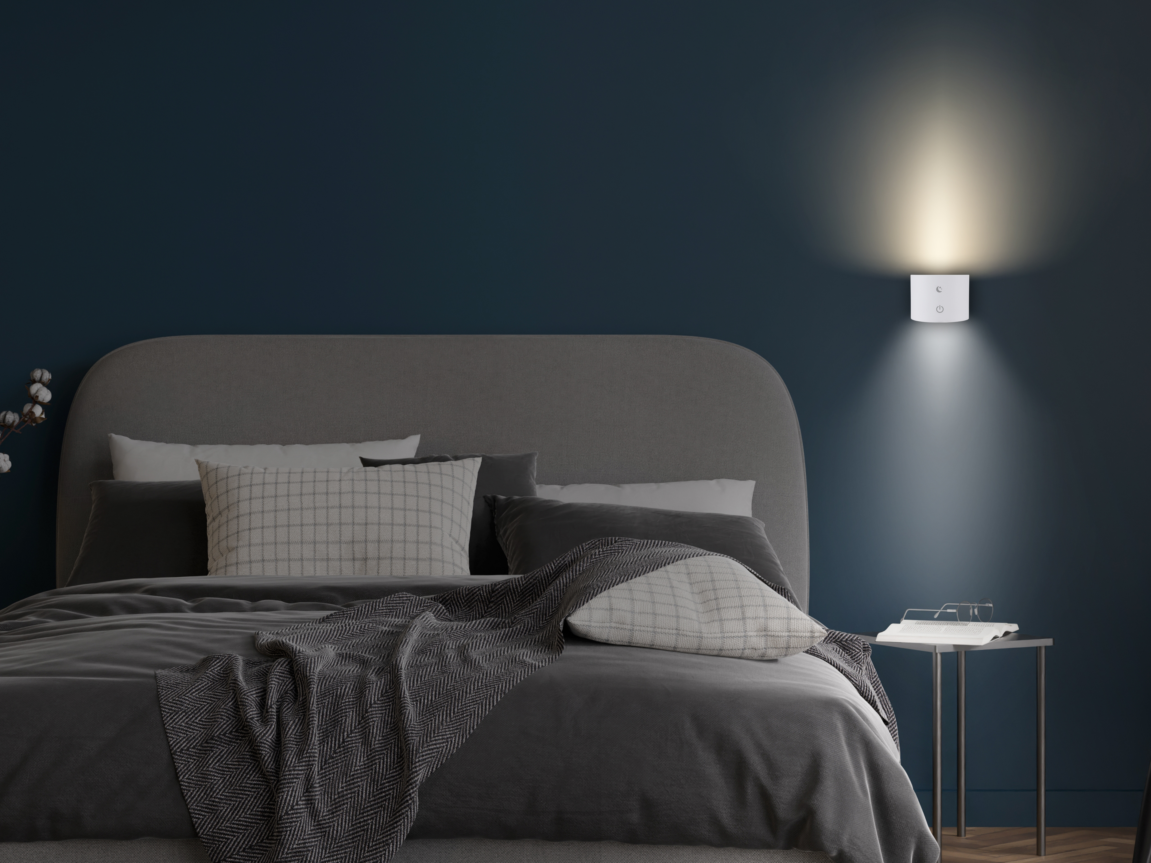 Camera da letto con letto, lampada e comodino. Copriletto e cuscini grigi. Lampada bianca su muro blu.