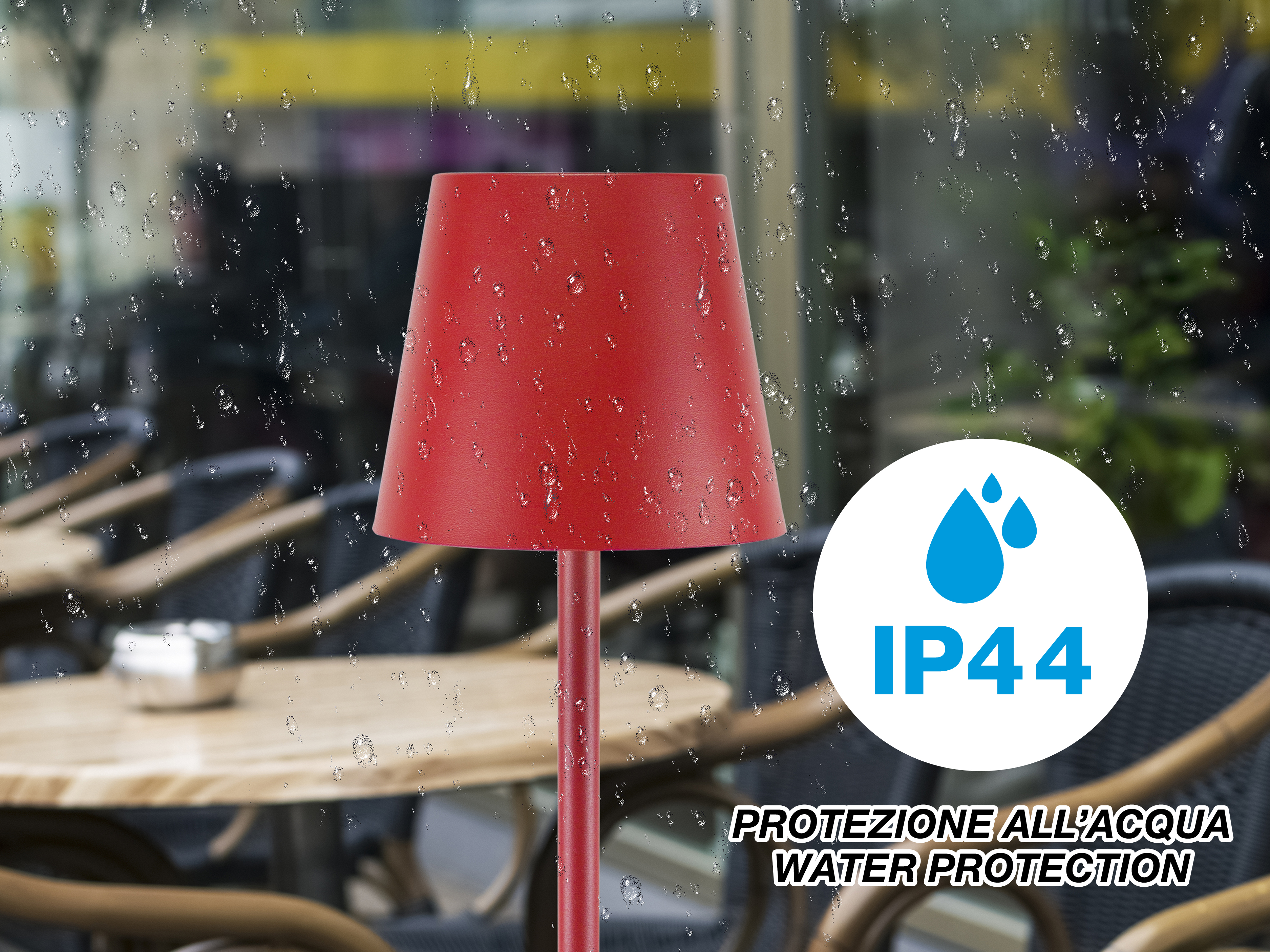 Una lampada rossa con gocce d'acqua, dietro un vetro con gocce d'acqua. Etichetta IP44 visibile.