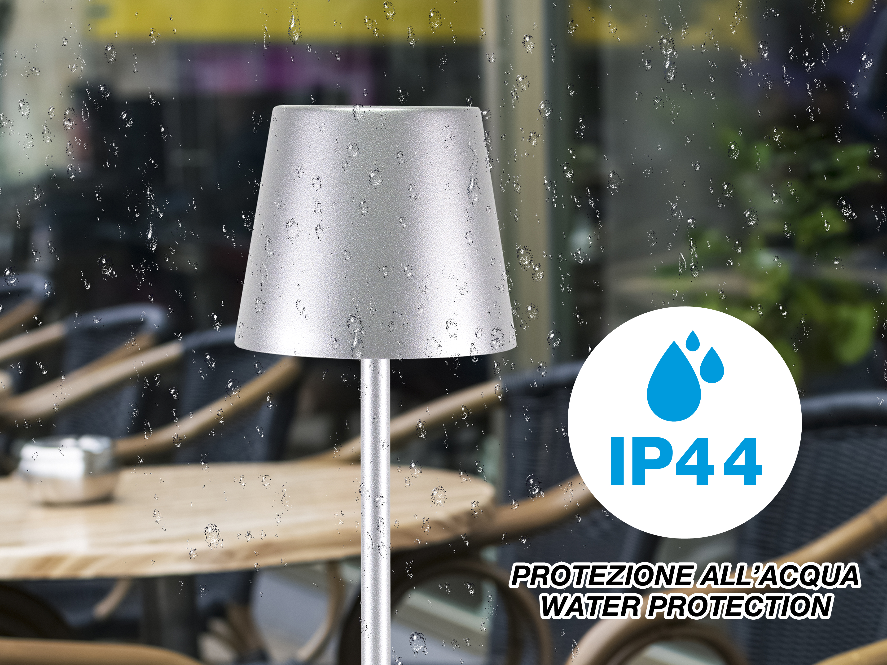 Una lampada argentata su un tavolo, con logo protezione IP44. Gocce di pioggia sulla finestra. Ristorante.