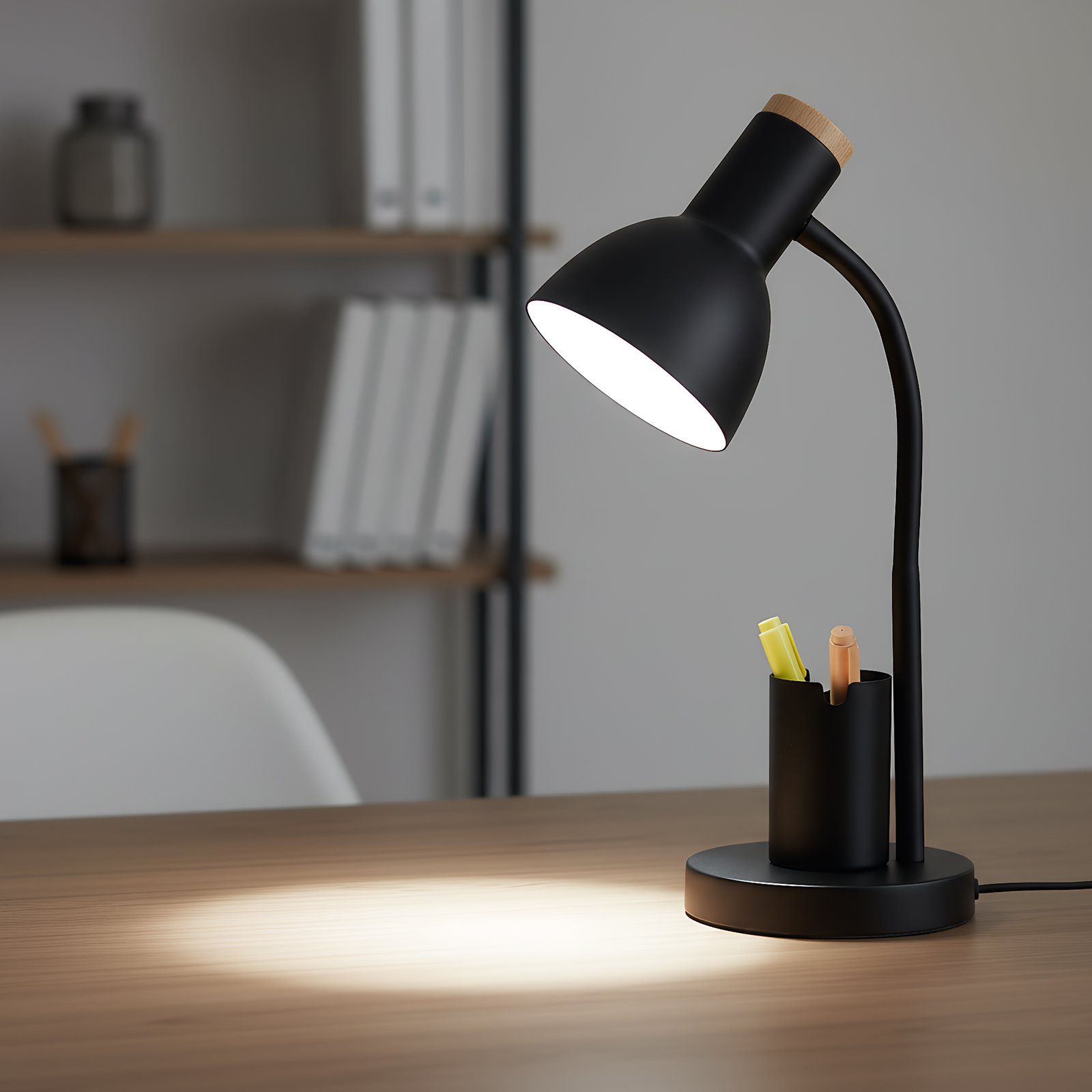 Eine schwarze Schreibtischlampe mit Holzakzent, die einen Holztisch beleuchtet. Ein Stifthalter mit Stiften ist sichtbar.