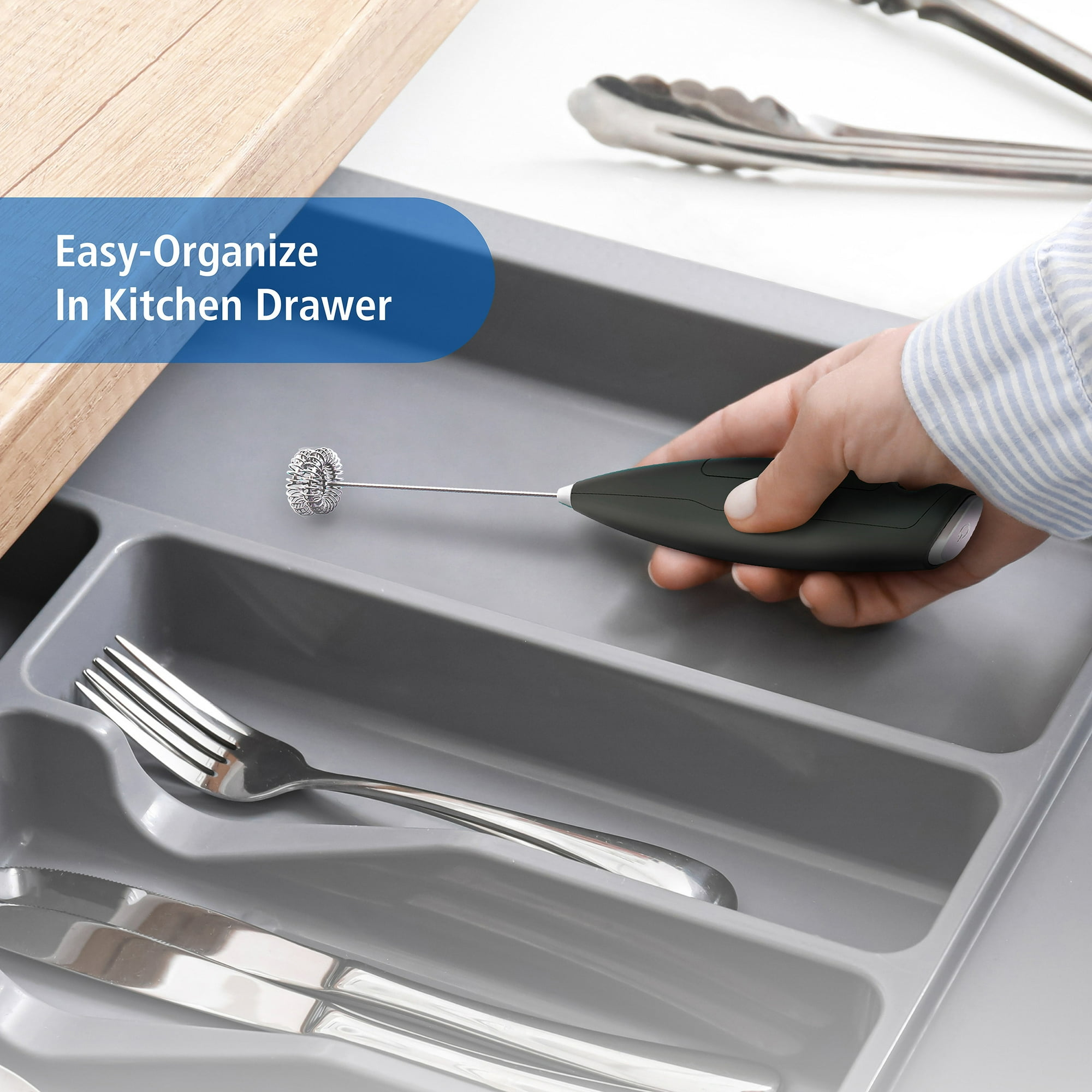 Eine Hand hält einen Aufschäumer in einer Schublade mit Utensilien. In der Schublade befinden sich Besteck und Zangen. Der Text lautet 'Easy-Organize'.