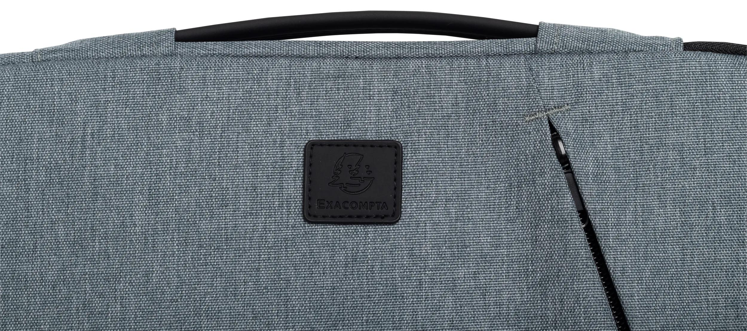 Primo piano di una borsa grigia con logo Exacompta. Visibili una cerniera e un manico neri, oltre al tessuto della borsa.