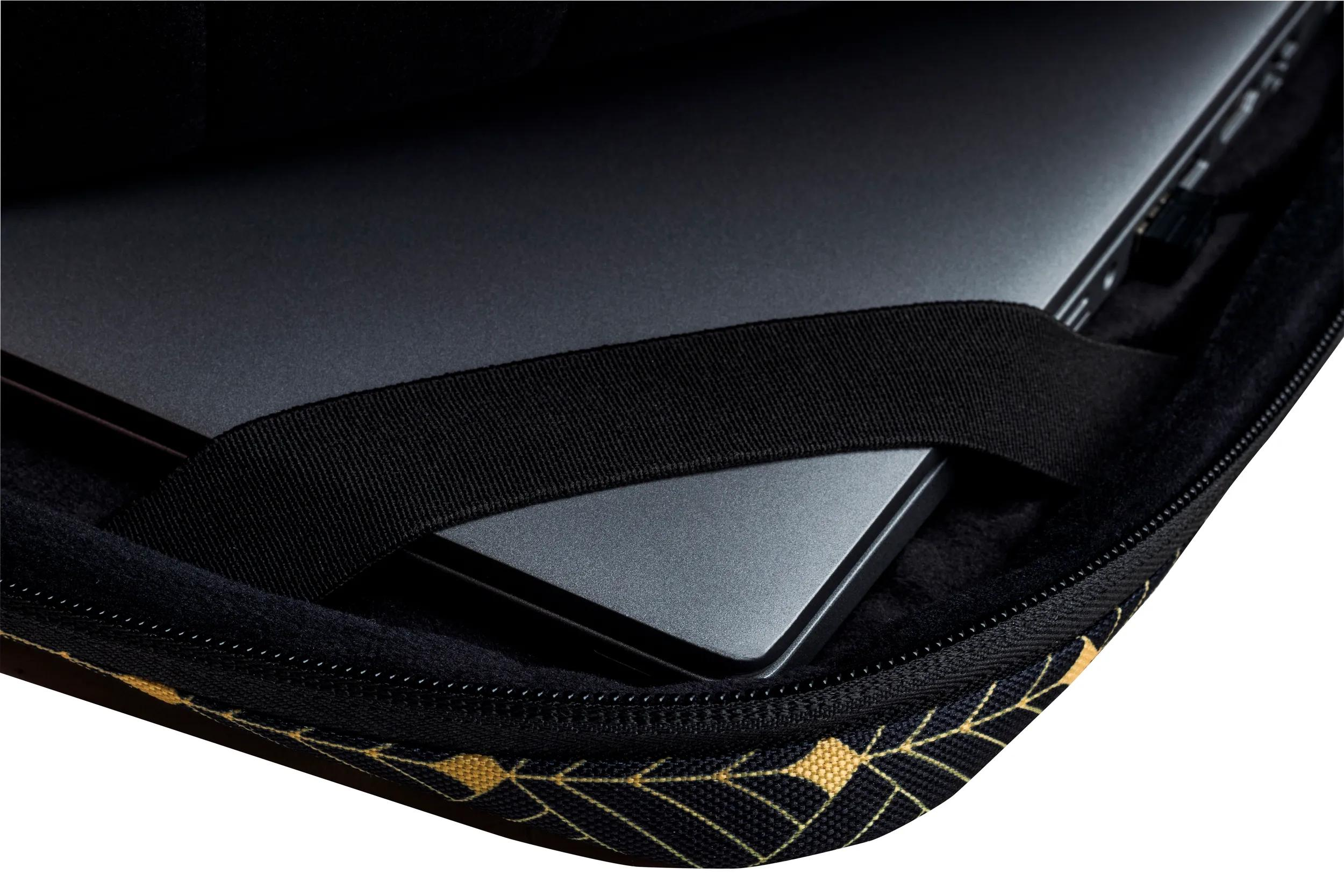 Un laptop all'interno di una custodia nera con un cinturino nero e un motivo di foglie d'oro. La custodia è aperta.