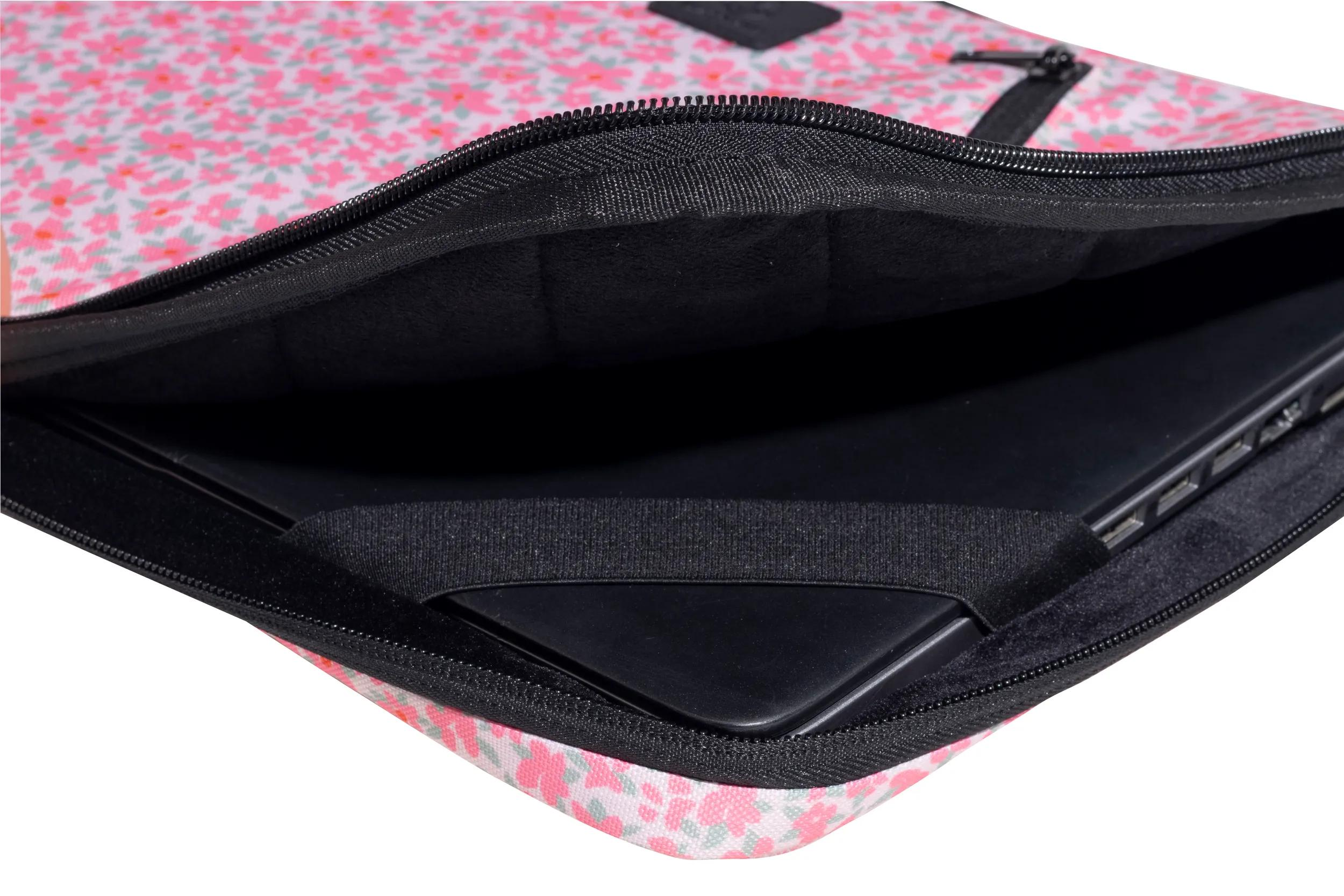 Portátil en una funda con estampado floral. La funda tiene una cremallera negra y un interior negro. El portátil es negro.
