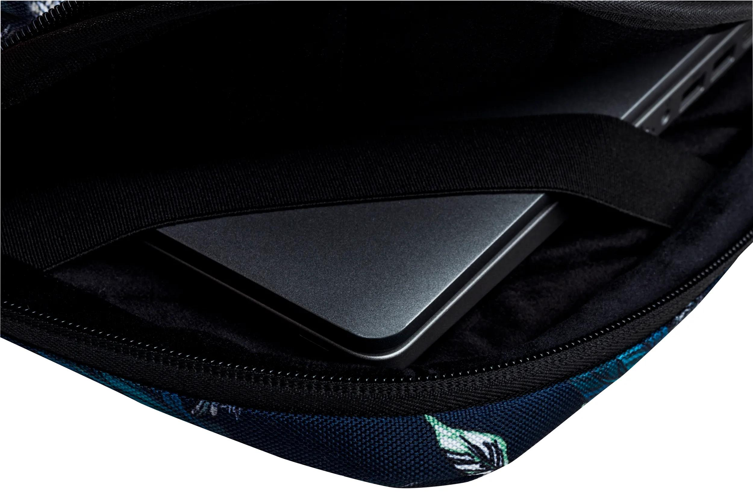 Laptop in una custodia. La custodia è blu navy con motivo floreale bianco e verde. Cerniera e cinturino neri visibili.