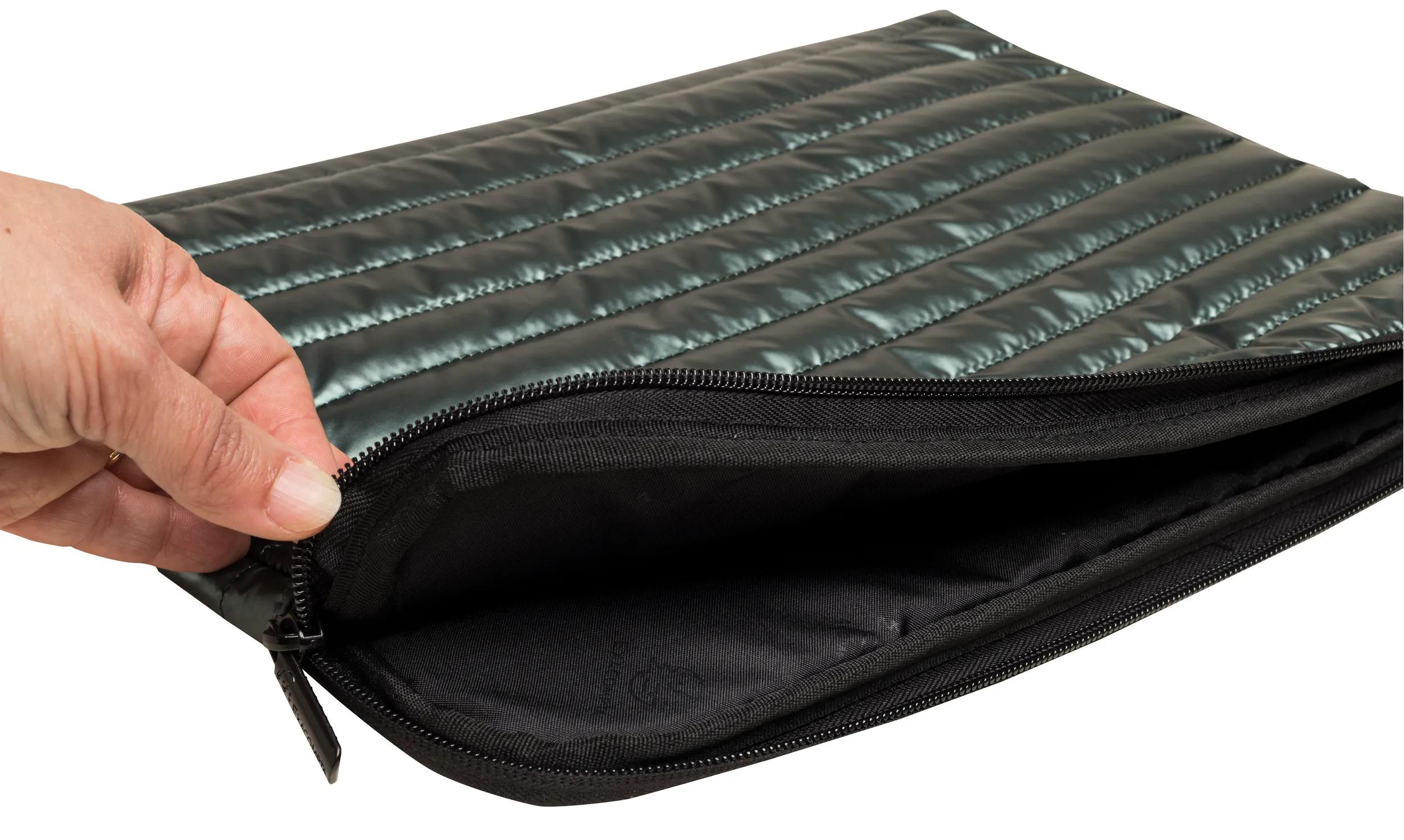Una mano abre una funda acolchada negra para portátil. La funda tiene cremallera e interior negro.