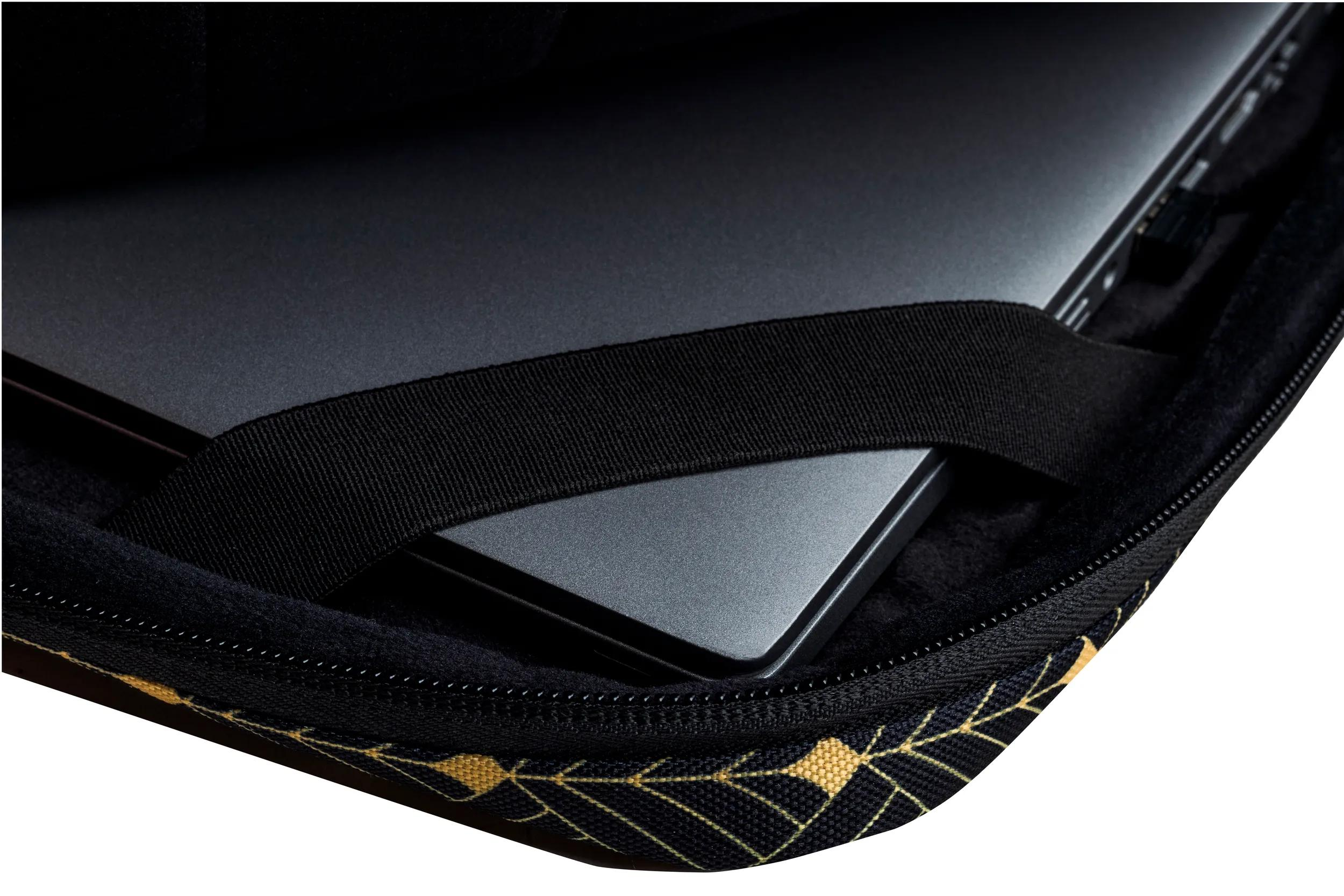 Laptop in una custodia nera con cinturino nero. La custodia ha un motivo oro e nero sul bordo inferiore.