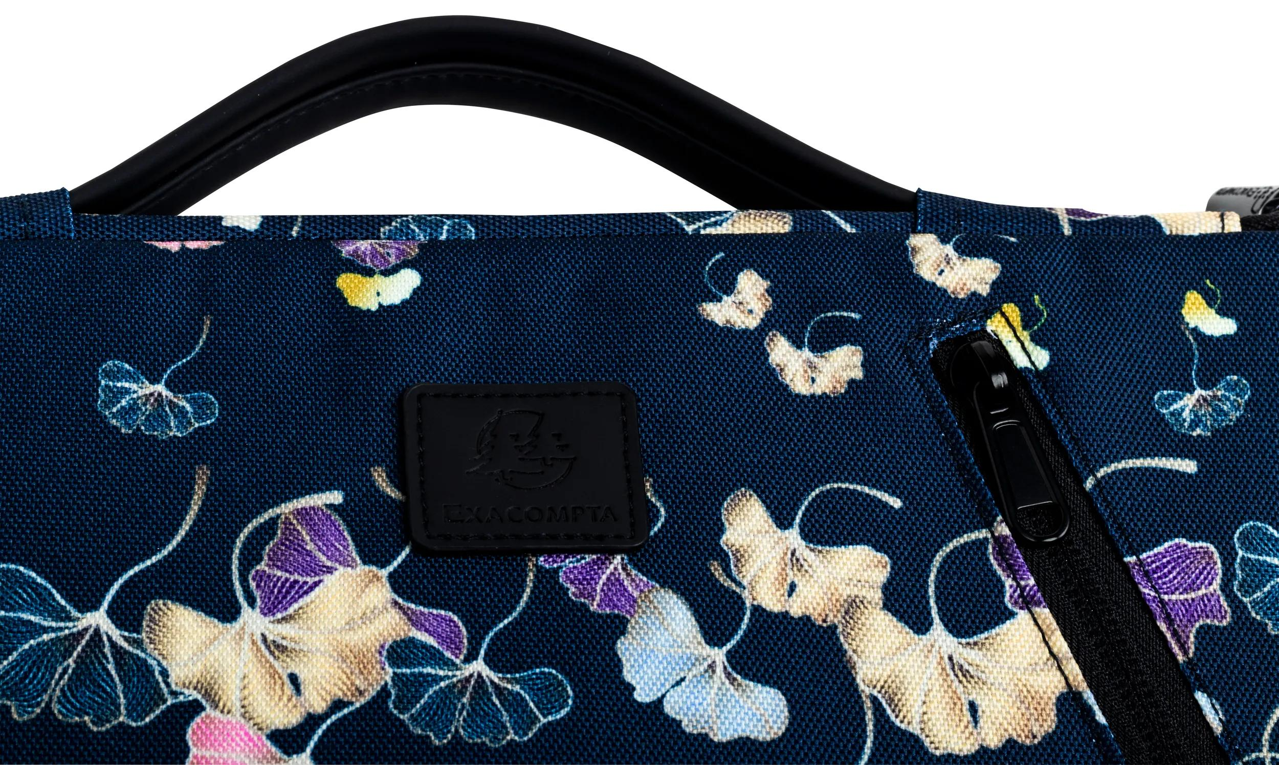 Primo piano di una borsa con motivo floreale, manico nero e cerniera. I fiori sono nelle tonalità del viola, giallo e blu.