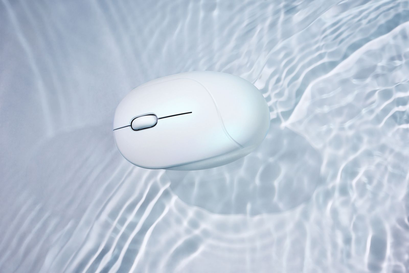Biała mysz komputerowa unosi się w wodzie. Woda ma zmarszczki, tworząc teksturowane tło. Mysz ma kółko przewijania.