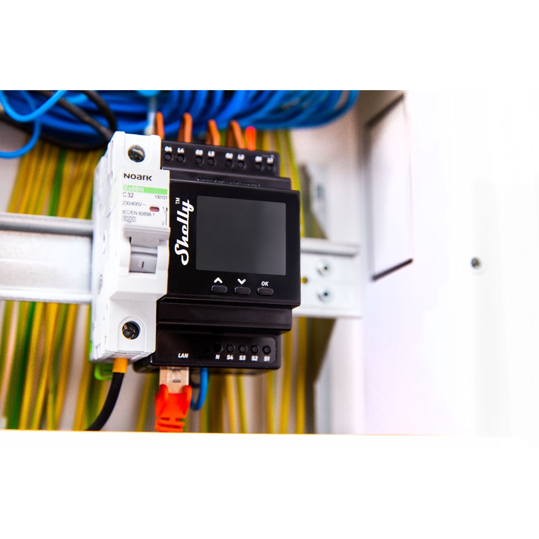 Panel elektryczny z wyłącznikiem, urządzeniem Shelly z ekranem i kablami sieciowymi. Widoczne są różne przewody.