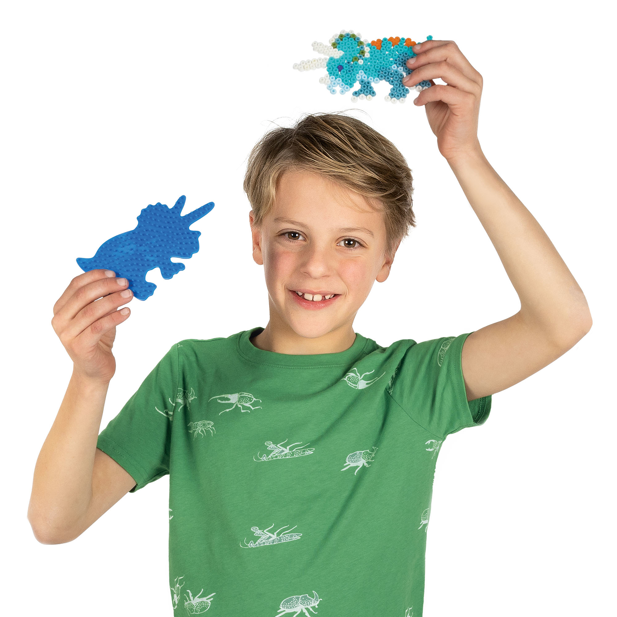 Un niño sostiene un triceratops azul y un dinosaurio con cuentas sobre su cabeza, vistiendo una camisa verde.