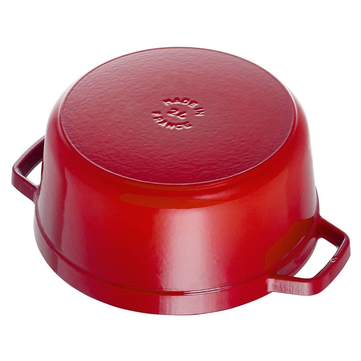 Una olla roja de hierro fundido está boca abajo. Tiene dos asas y son visibles las palabras 'MADE IN FRANCE'. La olla es brillante.