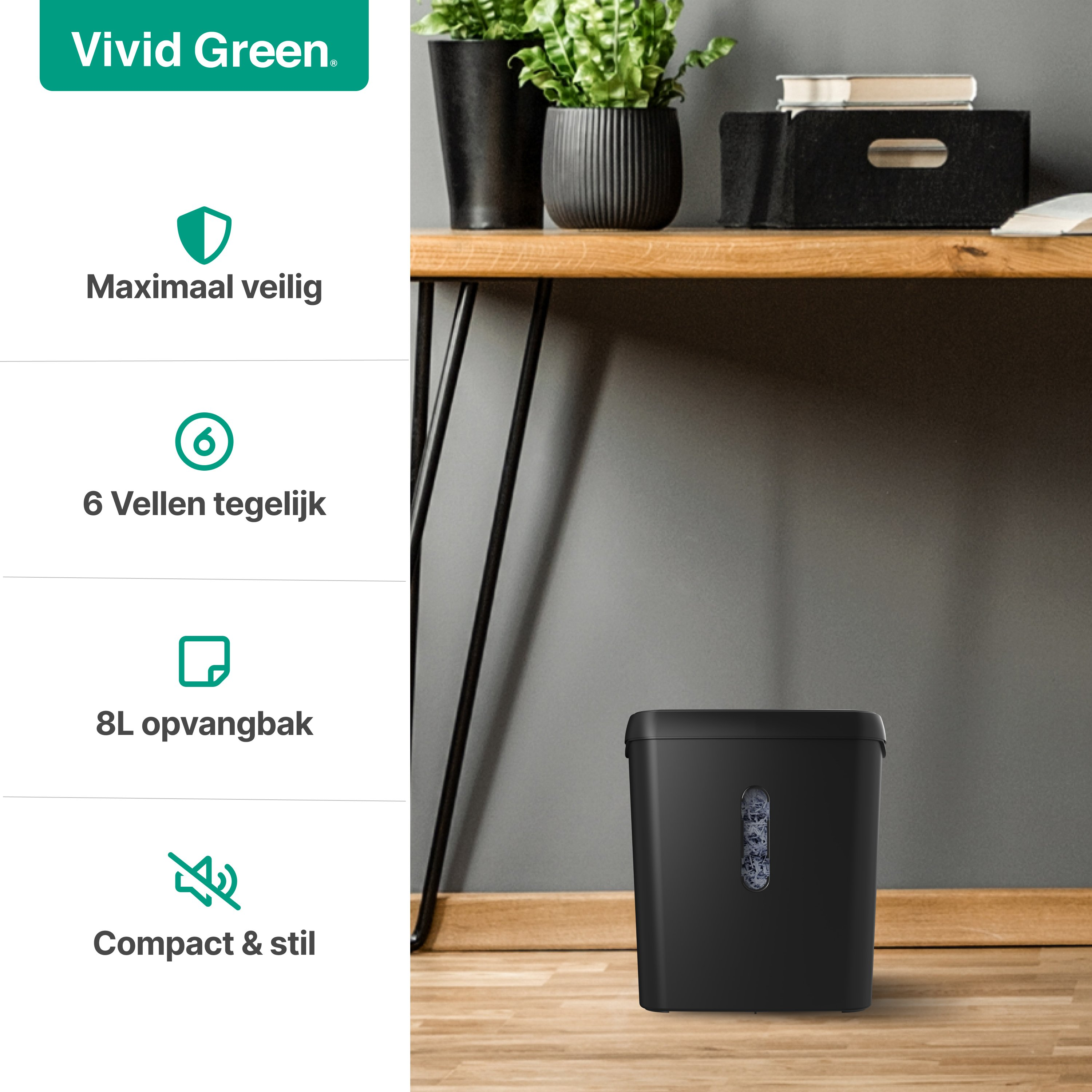 A black shredder on wooden floor. Green plants are in black pots on the desk. The wall is gray.
