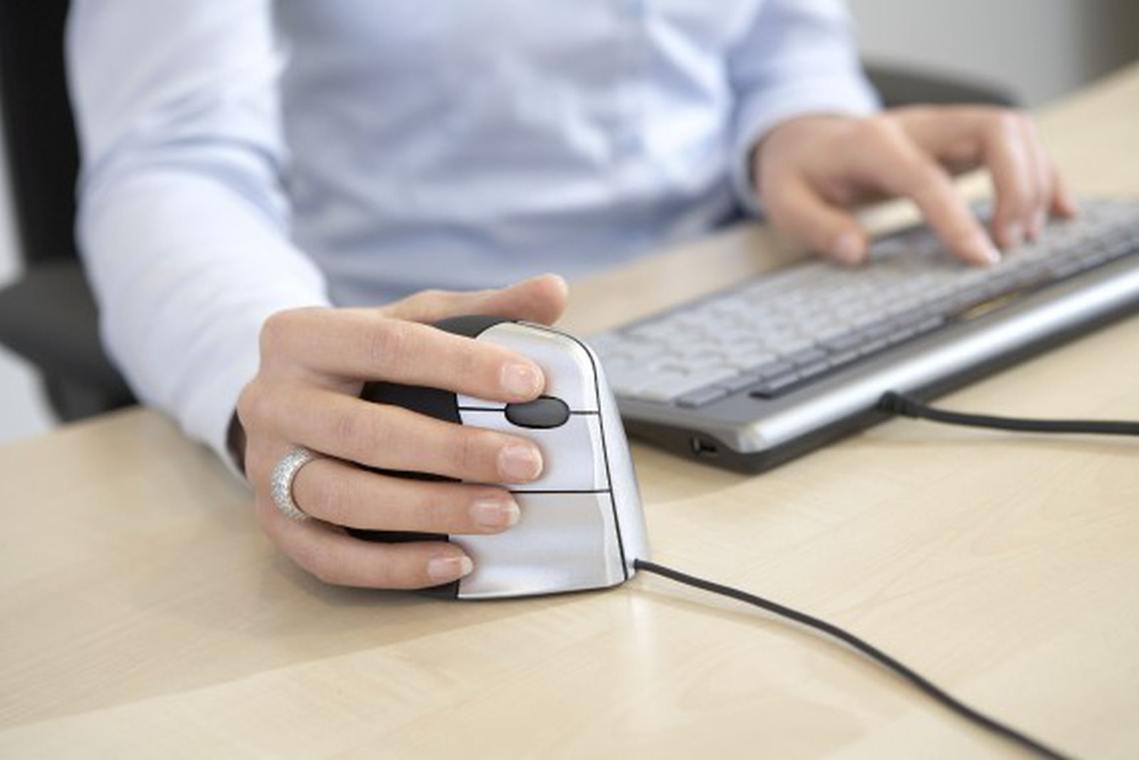 A person uses a computer mouse and keyboard. The person's hand rests on the mouse, while the other hand types on the keyboard.