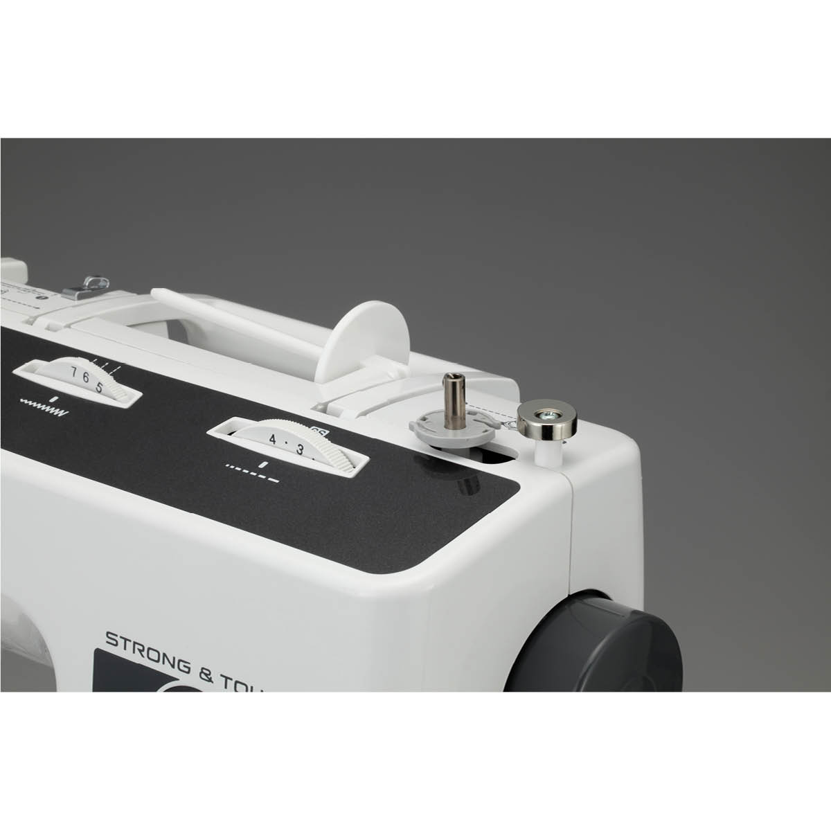 Biała maszyna do szycia z czarnymi akcentami. Posiada pokrętła, szpulkę i napisy 'STRONG & TO...' z boku. Szare tło.