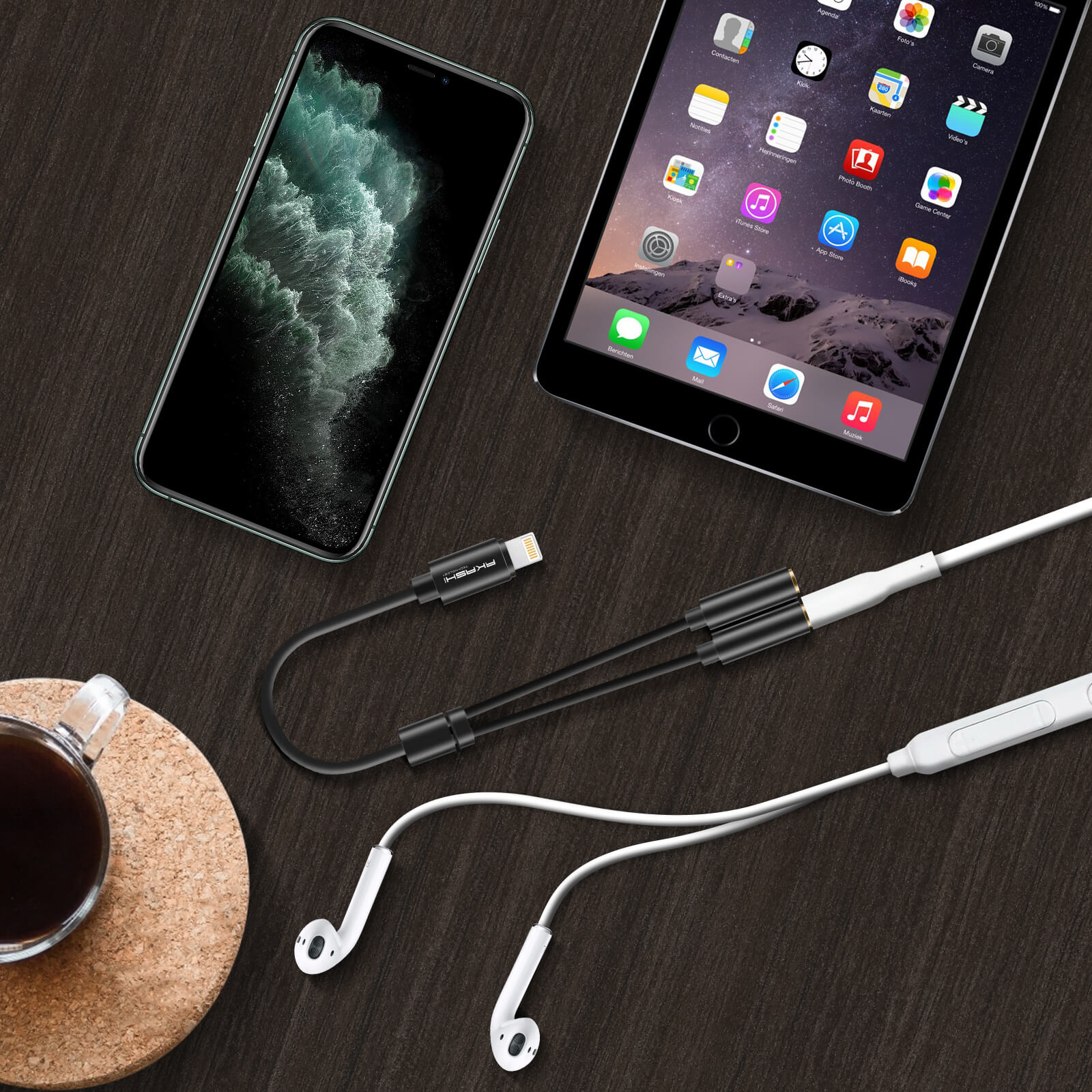 Un téléphone et une tablette sont posés sur une surface en bois avec un adaptateur pour casque et des écouteurs. Une tasse de café est à côté.