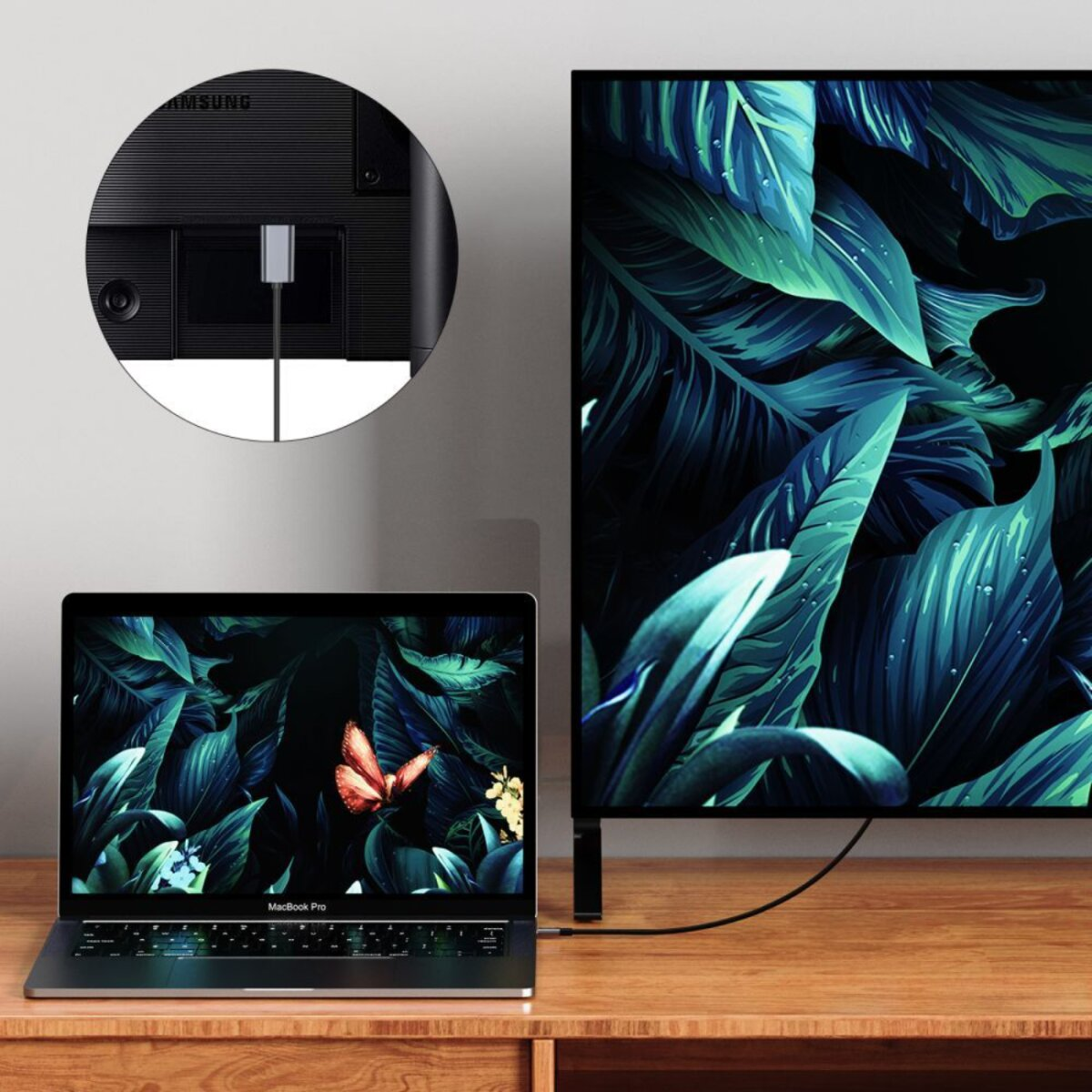 Un ordinateur portable connecté à un téléviseur affichant une image de papillon. Le téléviseur, l'ordinateur portable et le moniteur sont sur une table en bois.