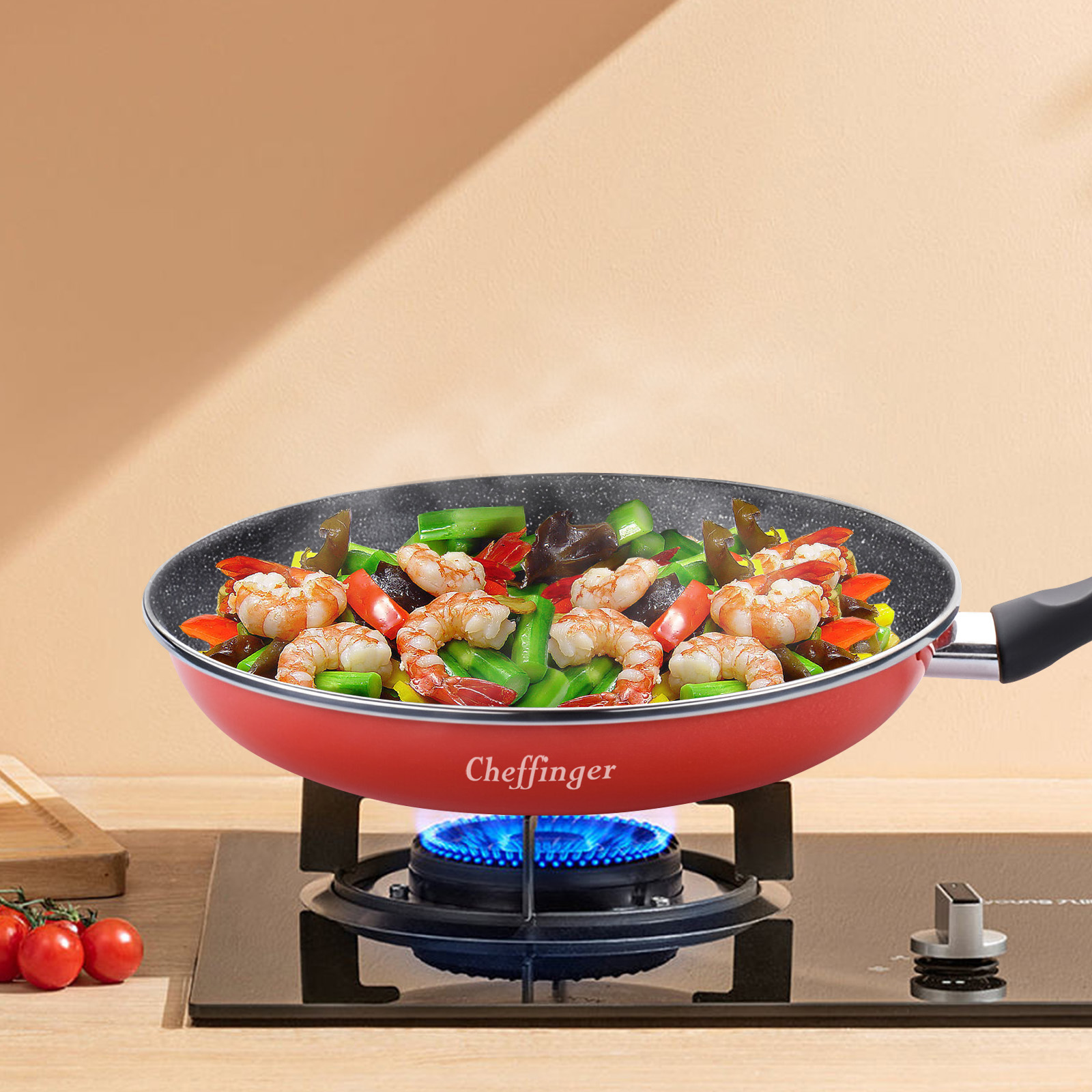Une poêle rouge avec des crevettes et des légumes sur une cuisinière à gaz, tomates à gauche.